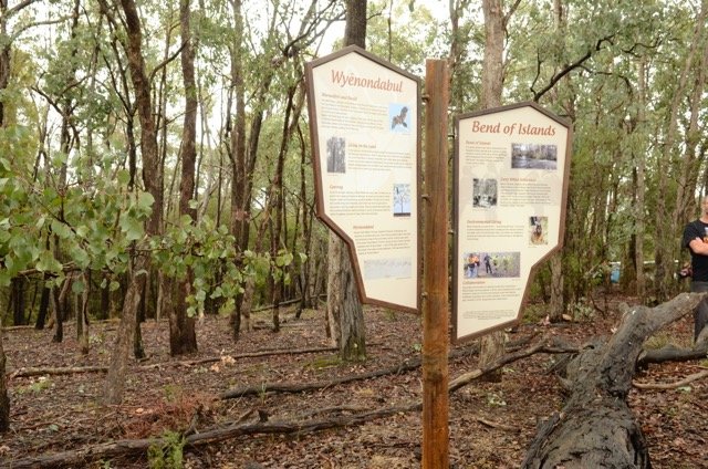 Information signs or display boards in a forest setting for Wyandotabuk and Bend of Islands, with trees and a person partially visible on the right.