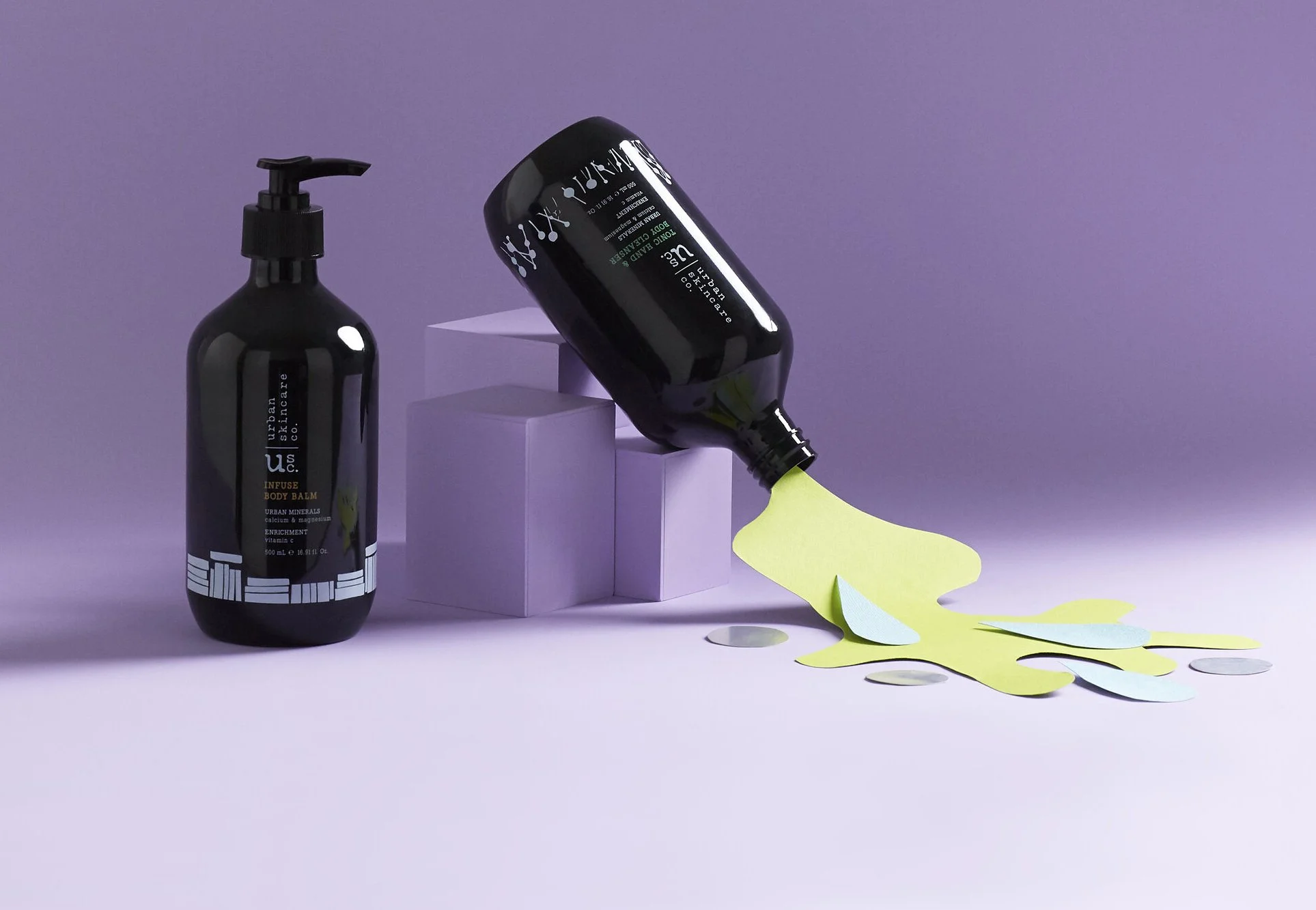 Photo of Urban Skincare is artistically placed against a purple backdrop with simulated spilling products which comprise of cut paper in green, blue and silver.