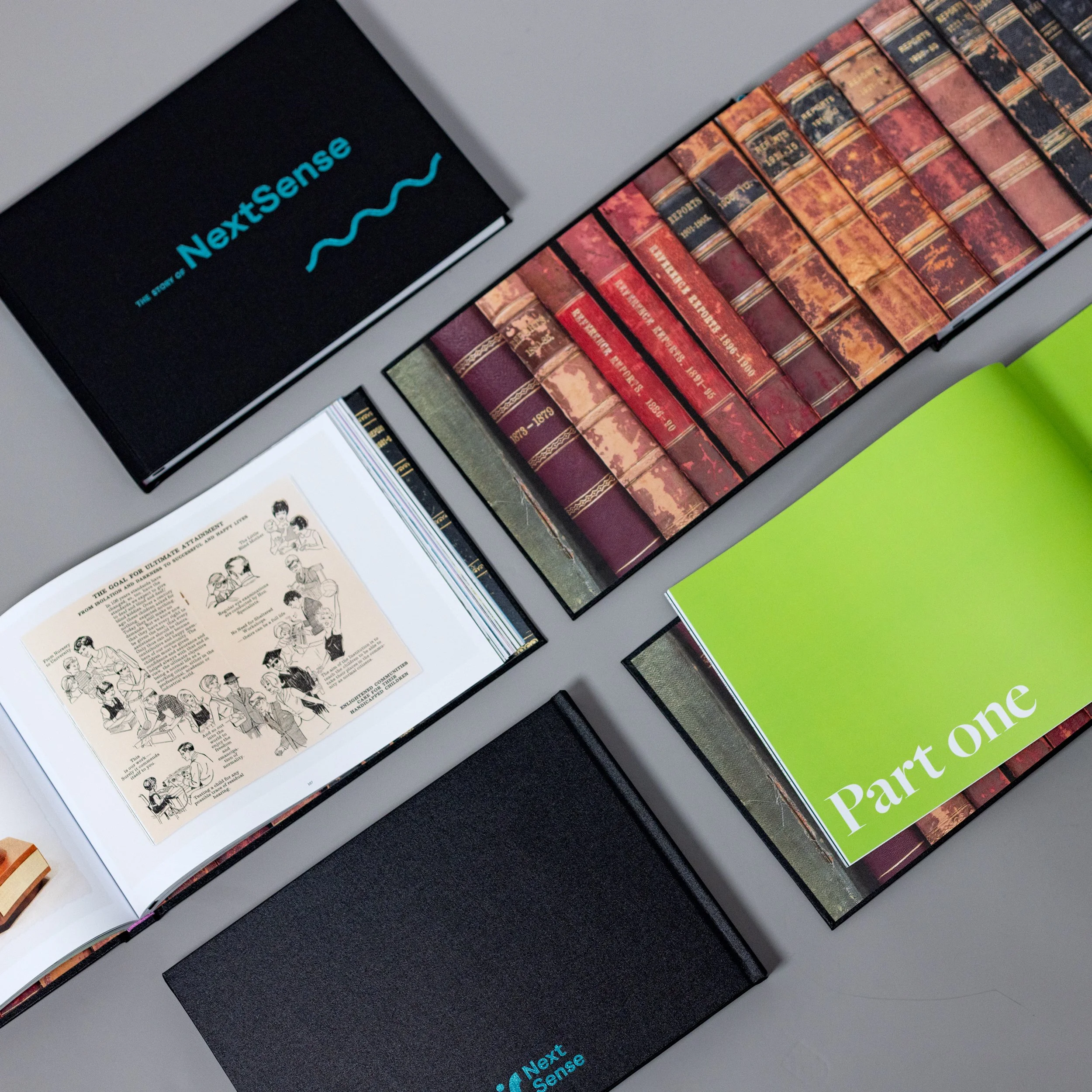 5 copies of the book "The story of NextSense", some of them open to internal pages, 2 of them showing the covers, is displayed.