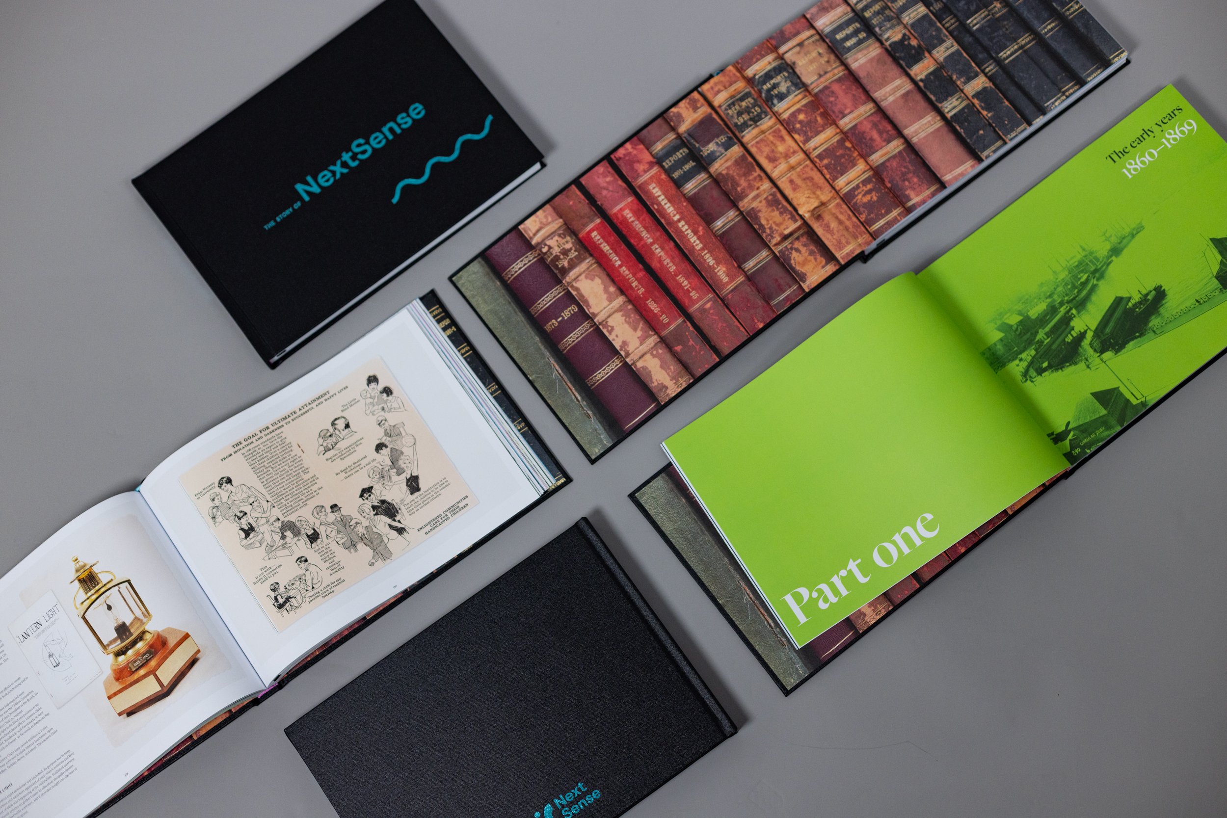 5 copies of the book "The story of NextSense", some of them open to internal pages, 2 of them showing the covers, is displayed.