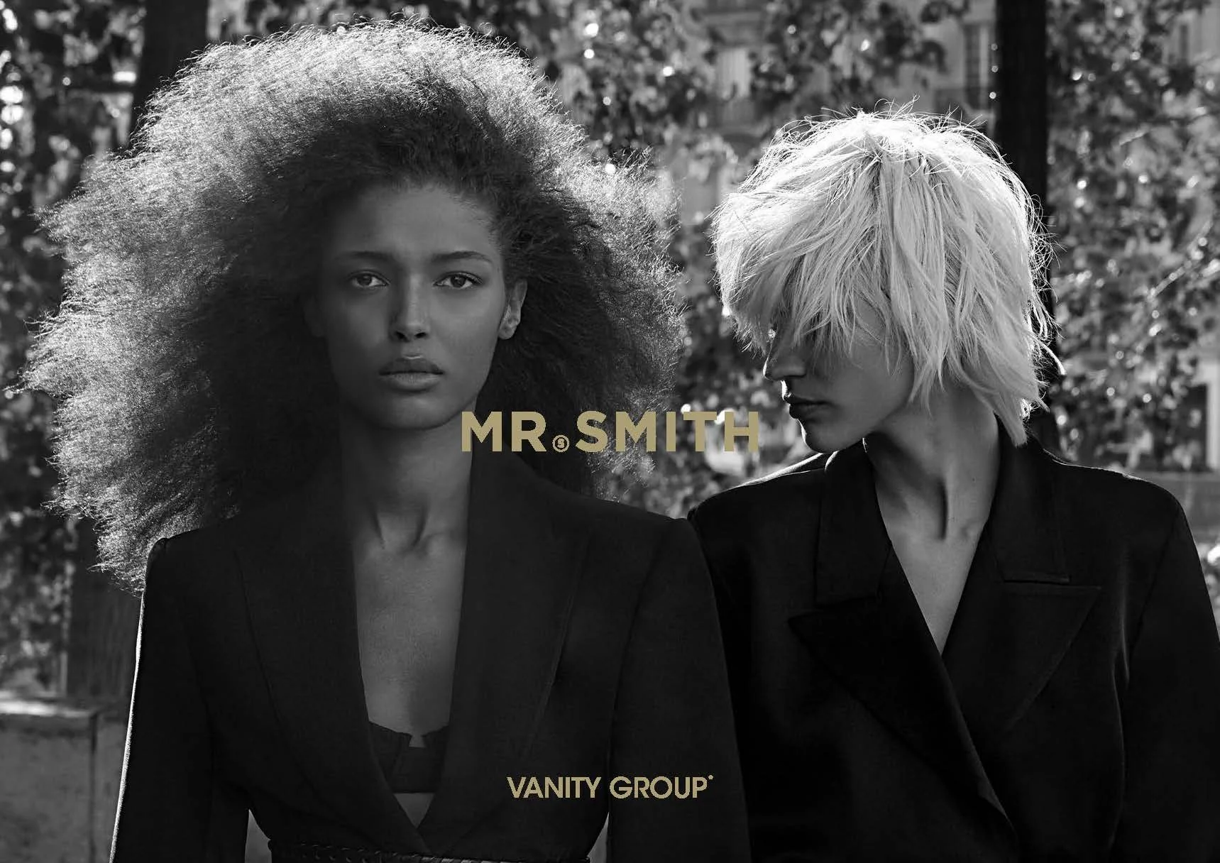Black and white image of two women with great hair in the outdoors. 2 logos Mr Smith and Vanity Group are on the image. Mr Smith is more prominent.