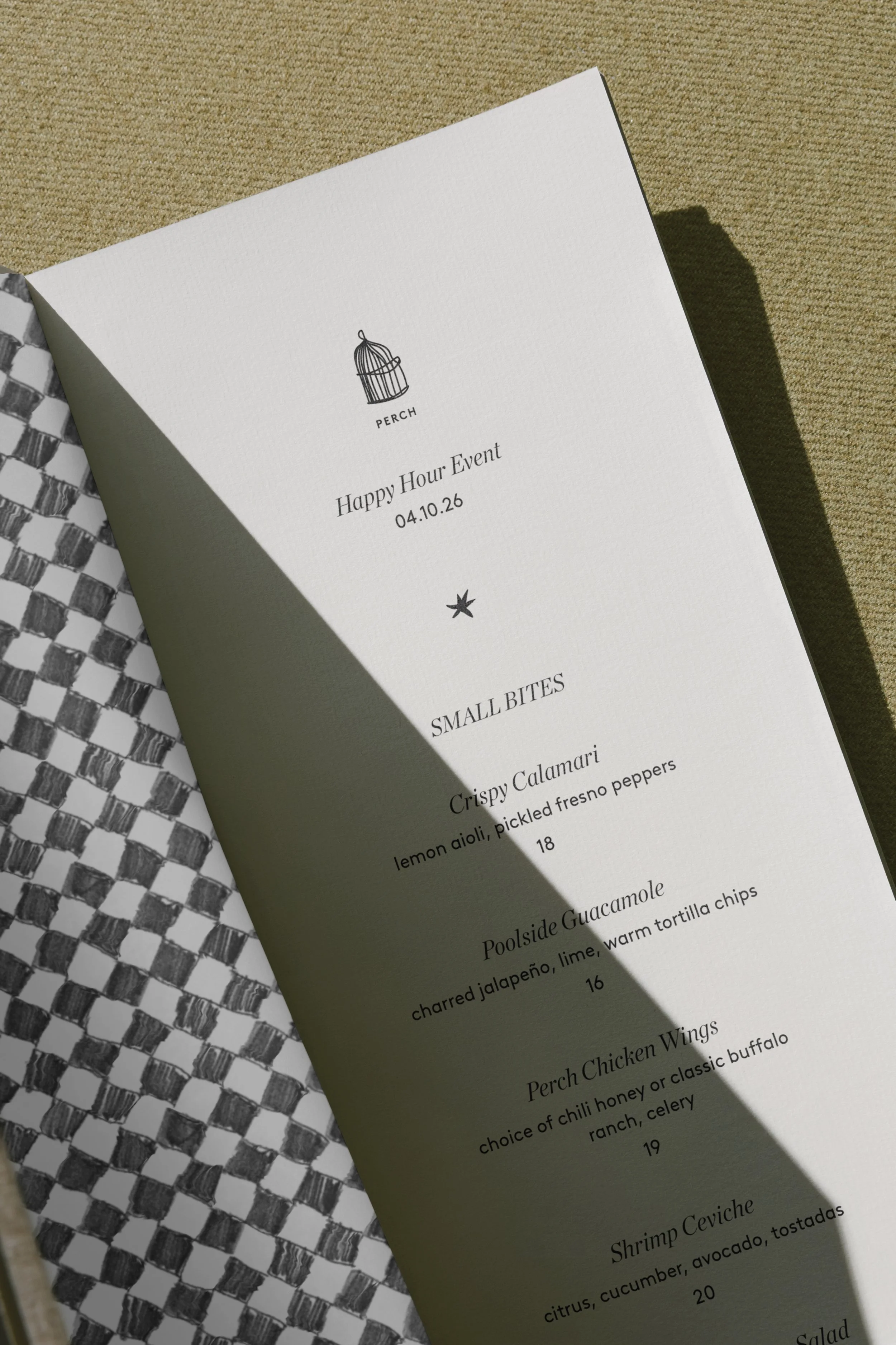 A white menu card with black text and a small birdcage illustration at the top, titled 'Happy Hour Event 04.10.26,' listing small bites including crispy calamari, poolside guacamole, perch chicken wings, and shrimp ceviche, with descriptions and prices.
