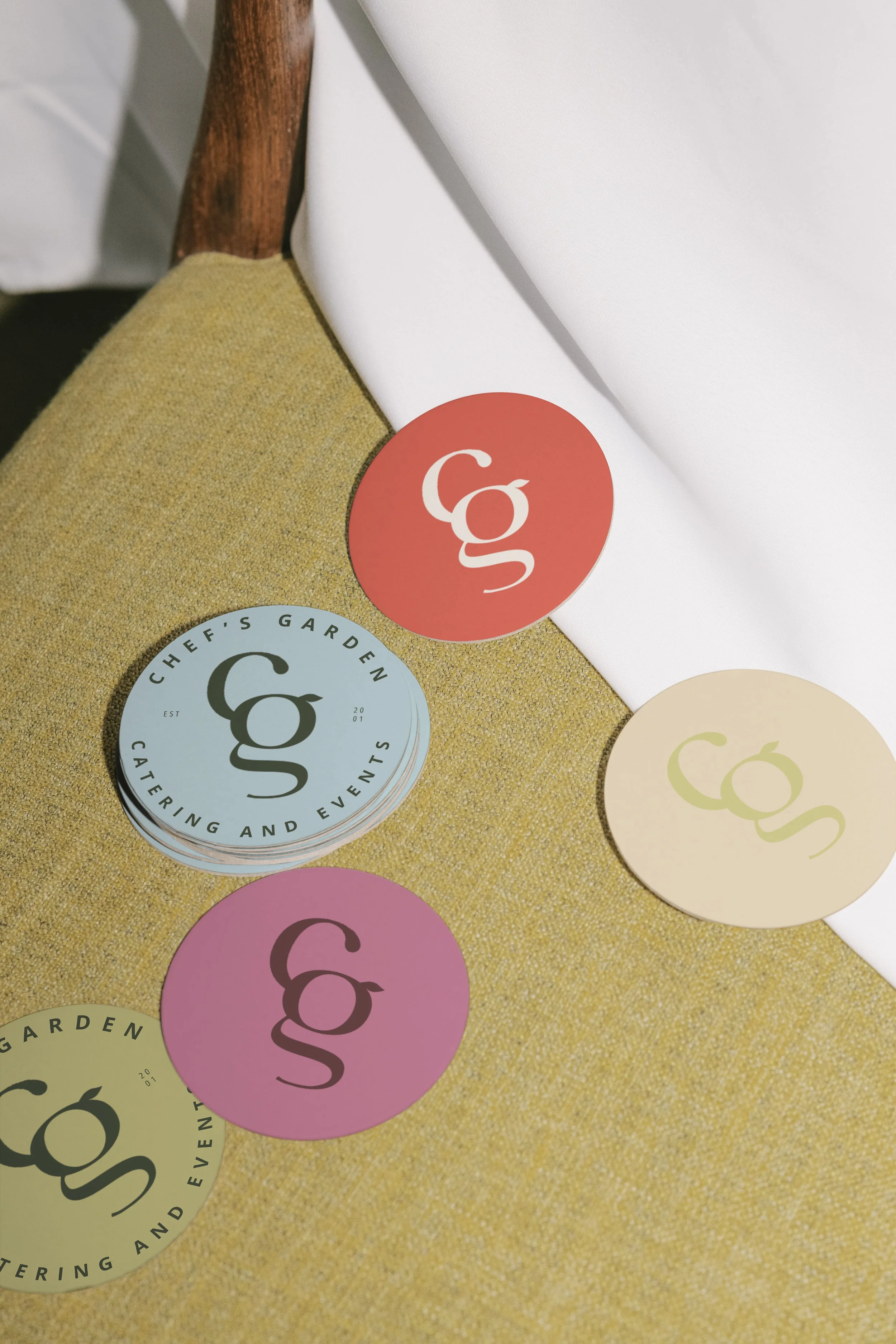 Round buttons with the logo 'cg' in different colors on a yellow and white surface.