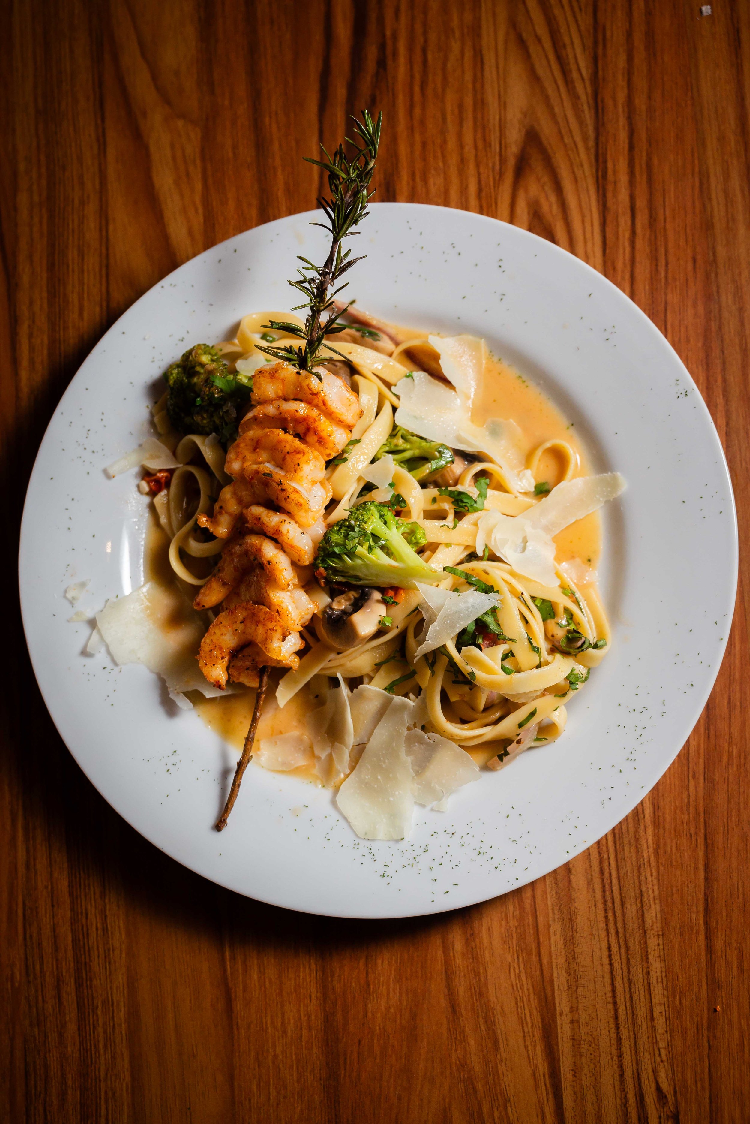 Brocheta de camarones posada sobre una pasta de verduras y salsa.