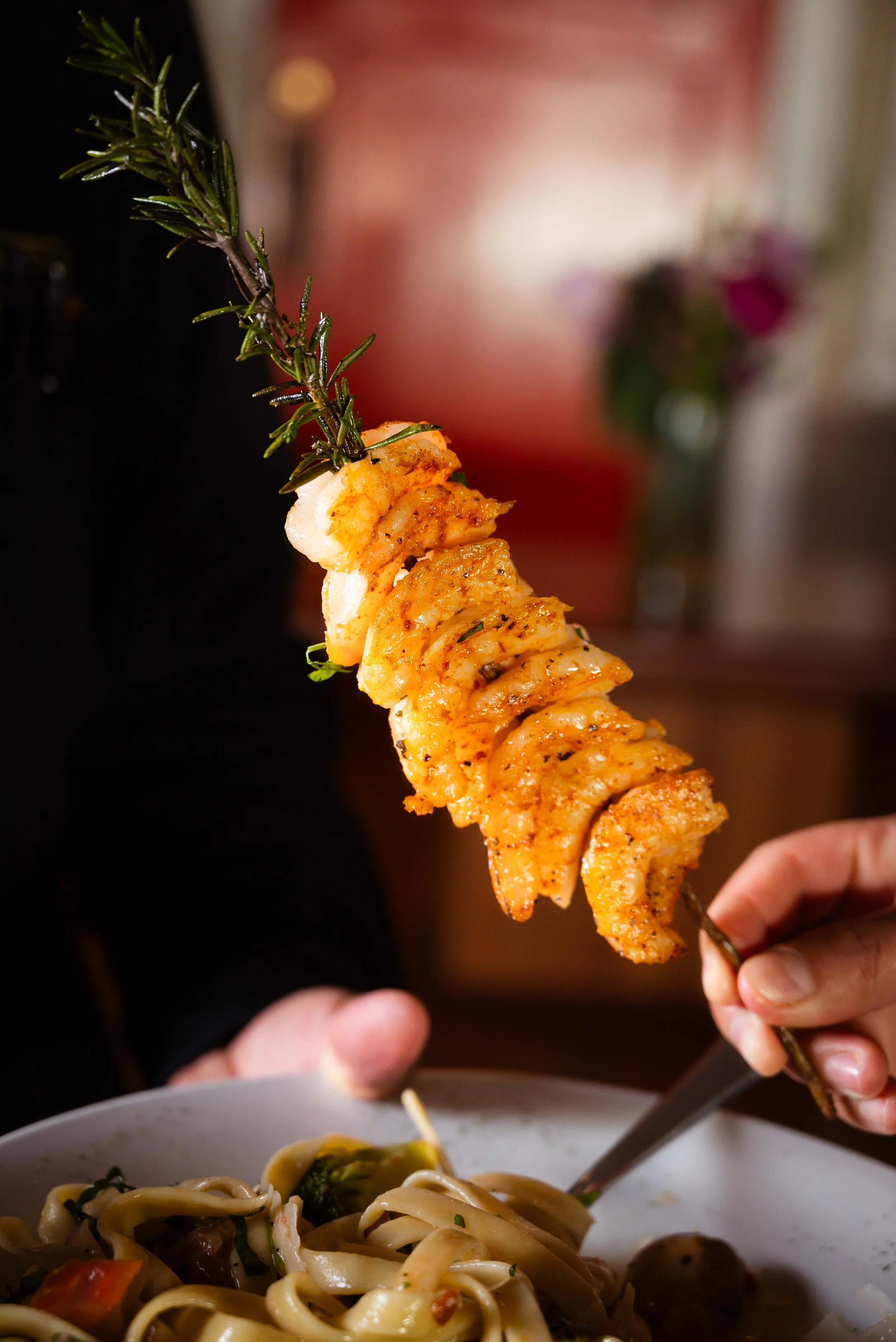 Pasta con verduras y una brocheta de camarones asados.