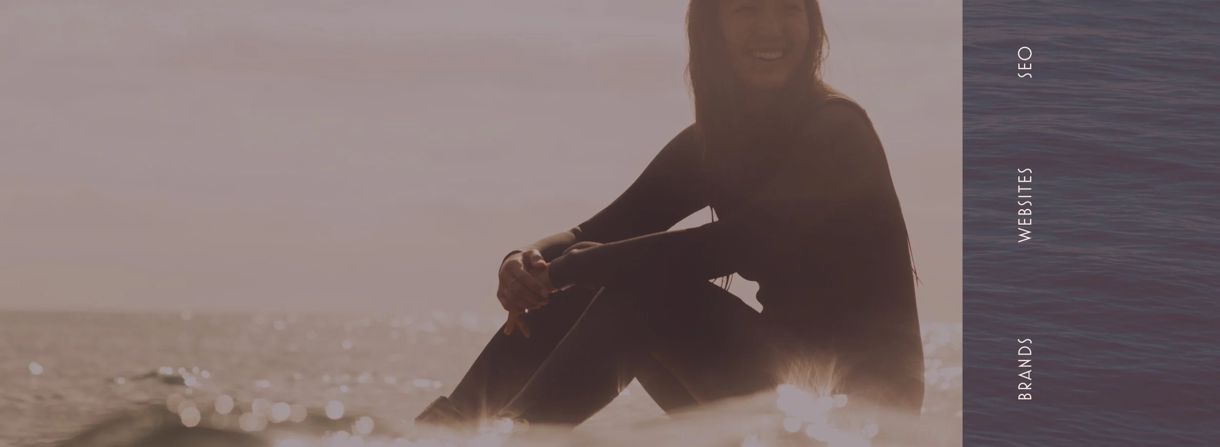  A female surfer sitting on her board in the ocean. This is part Aamu Creative Studio feeling and branding in Bend Oregon.