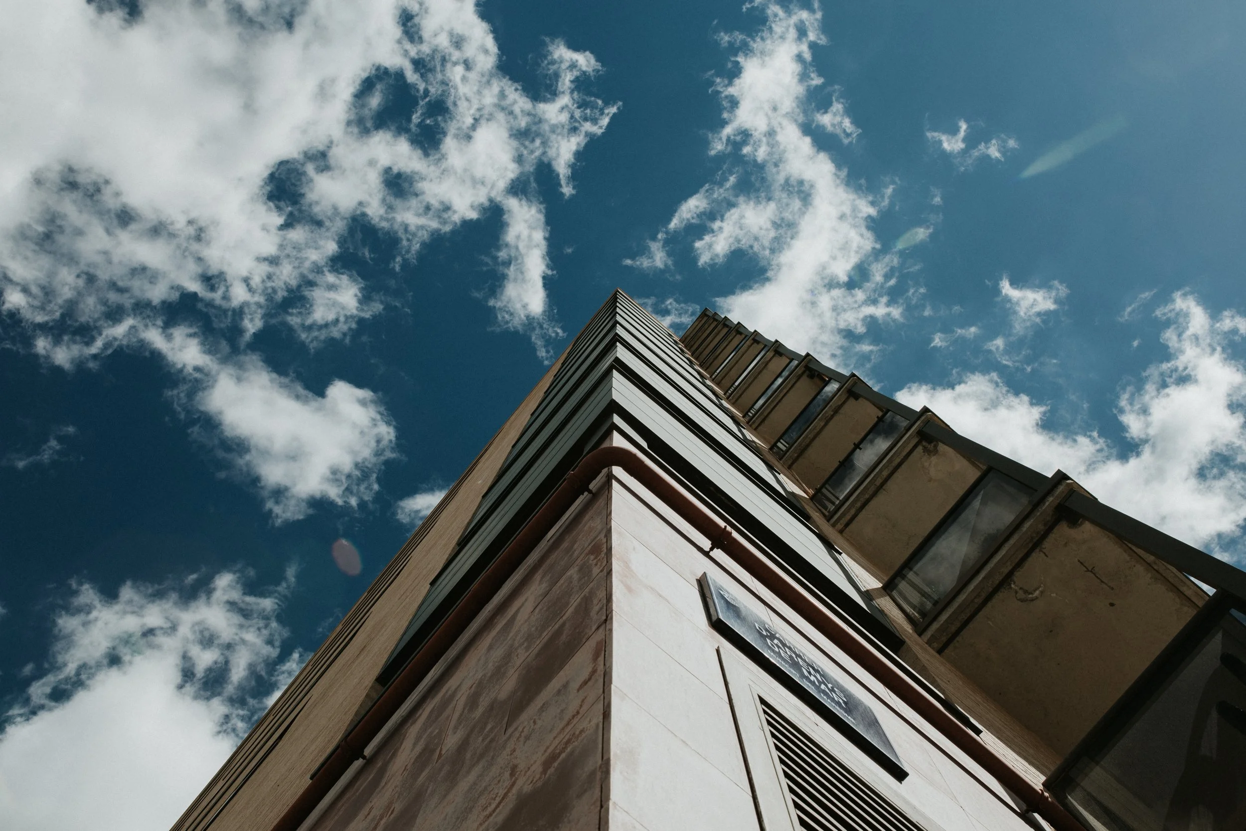 low-angle-shot-high-rise-building-clear-blue-sky-with-white-clouds.jpg