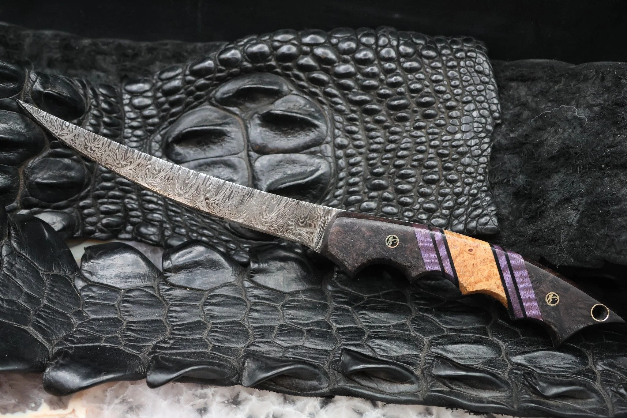 Did someone say Fillet??

Check out this Damascus fillet we just finished up. 
It features black dyed redwood burl, purple dyed mango, and spalted maple with awesome fishermen mosaic pins. 

This particular piece will stay with us, as our household i