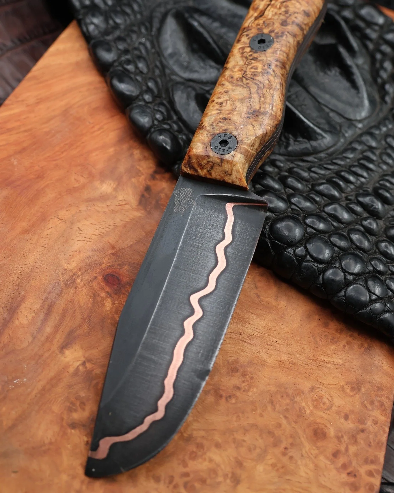 This custom hunter started its journey at Iron Beak Forge in Indiana, where the steel billet was hand forged from mono steel stacked around copper, creating that striking copper line flowing through the blade.

Once it arrived in Texas, we shaped and