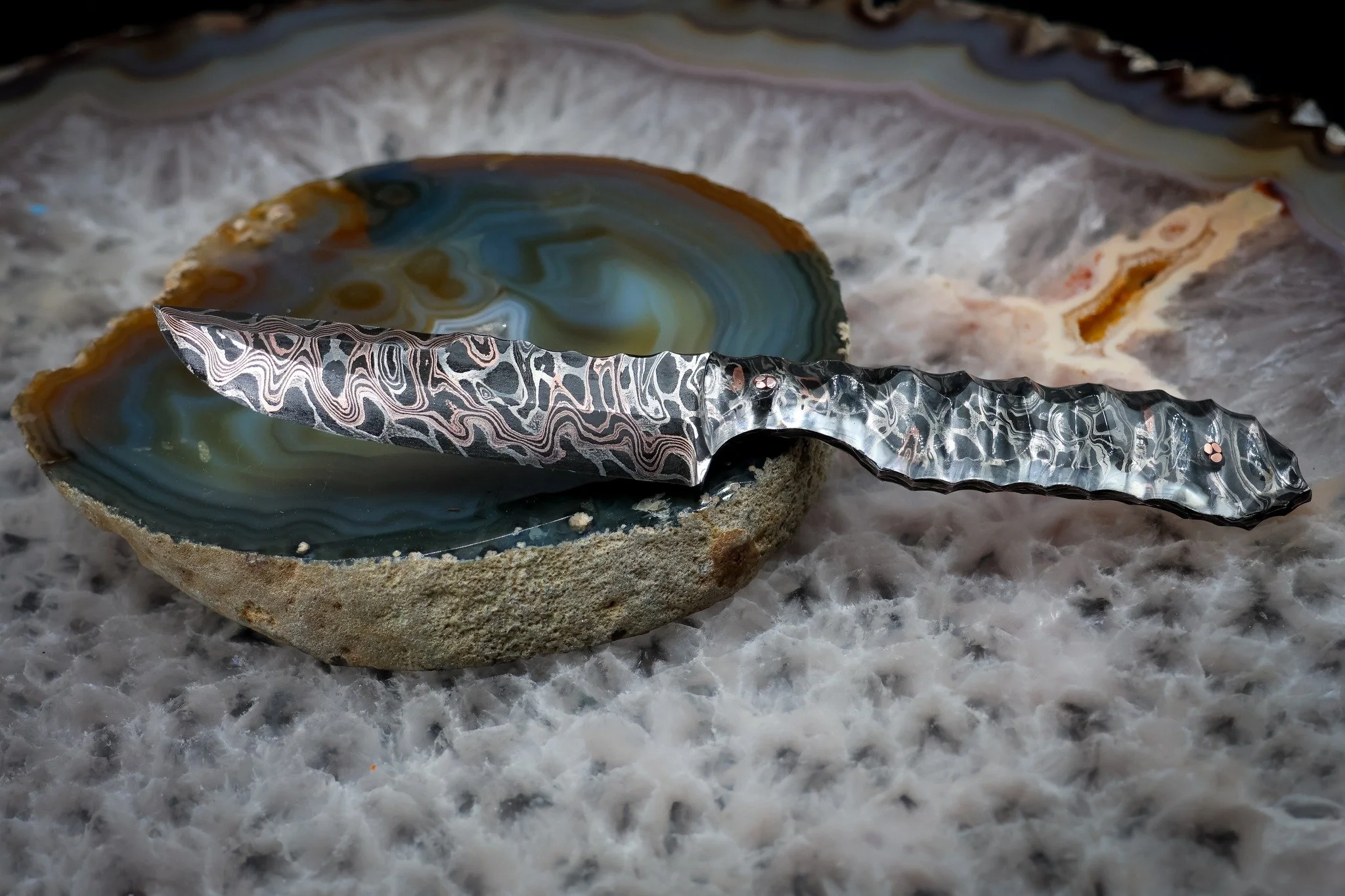 Some steel just refuses to be covered up.

With this dragon core, layered copper and 1080 from Adam Deville, we couldn't bring ourselves to hide half of it behind a traditional handle. So we went clear.

Clear acrylic keeps the pattern visible all th