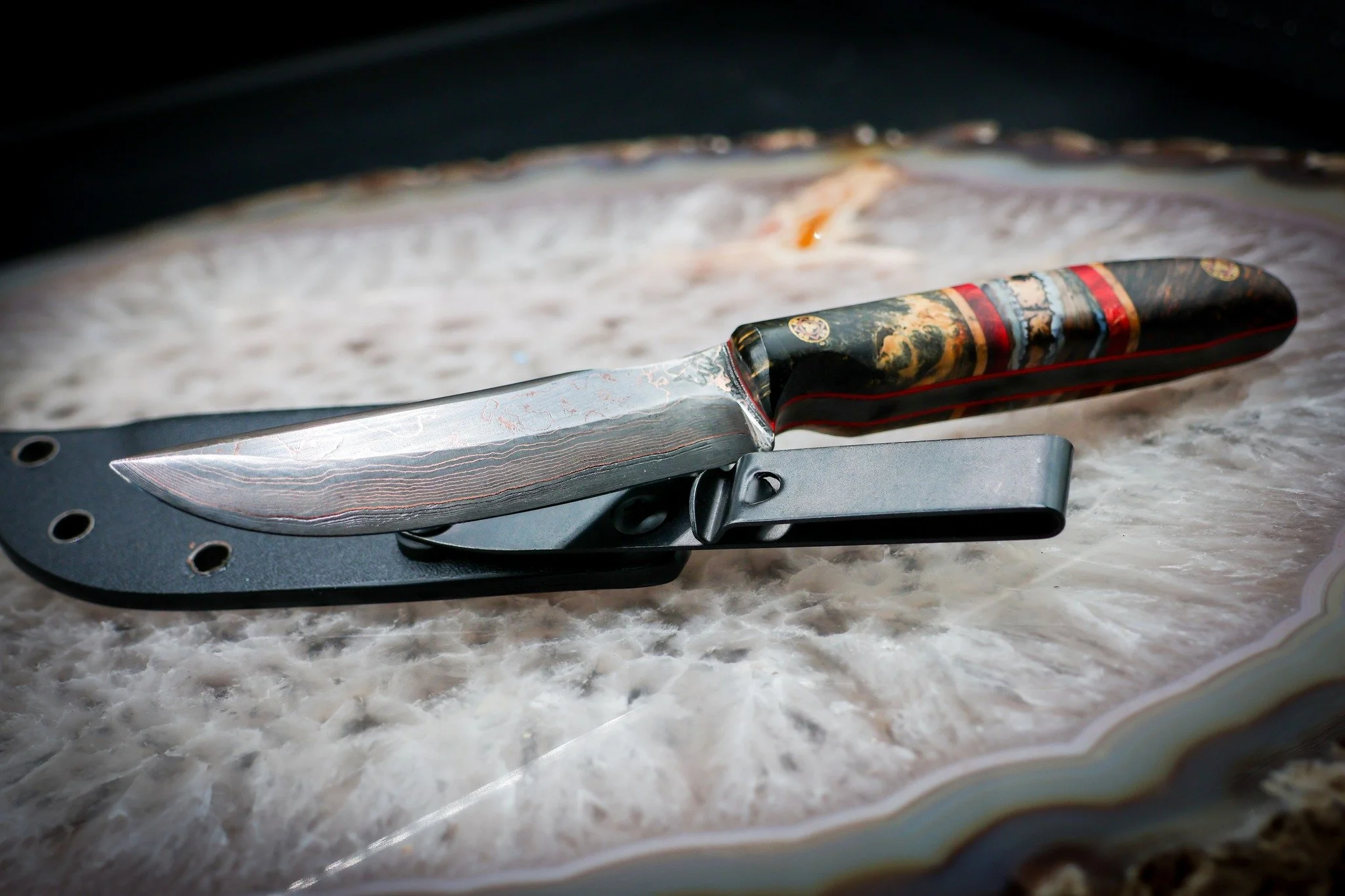 There are FOUR different materials hiding in this handle. 👀

Buckeye, red dyed mango, blonde spalted maple... and segmented mammoth molar.

Yep. Mammoth. 🦣

We paired them with layered 1080 and copper Damascus, letting the red and warm tones in the