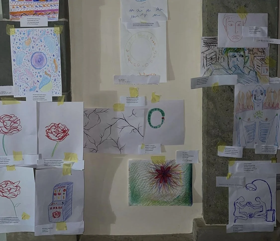 Collection of sketches and drawings attached to a wall with yellow tape, including abstract shapes, faces, flowers, and other artistic designs. MARIAM KVASHILAVA EXHIBITION