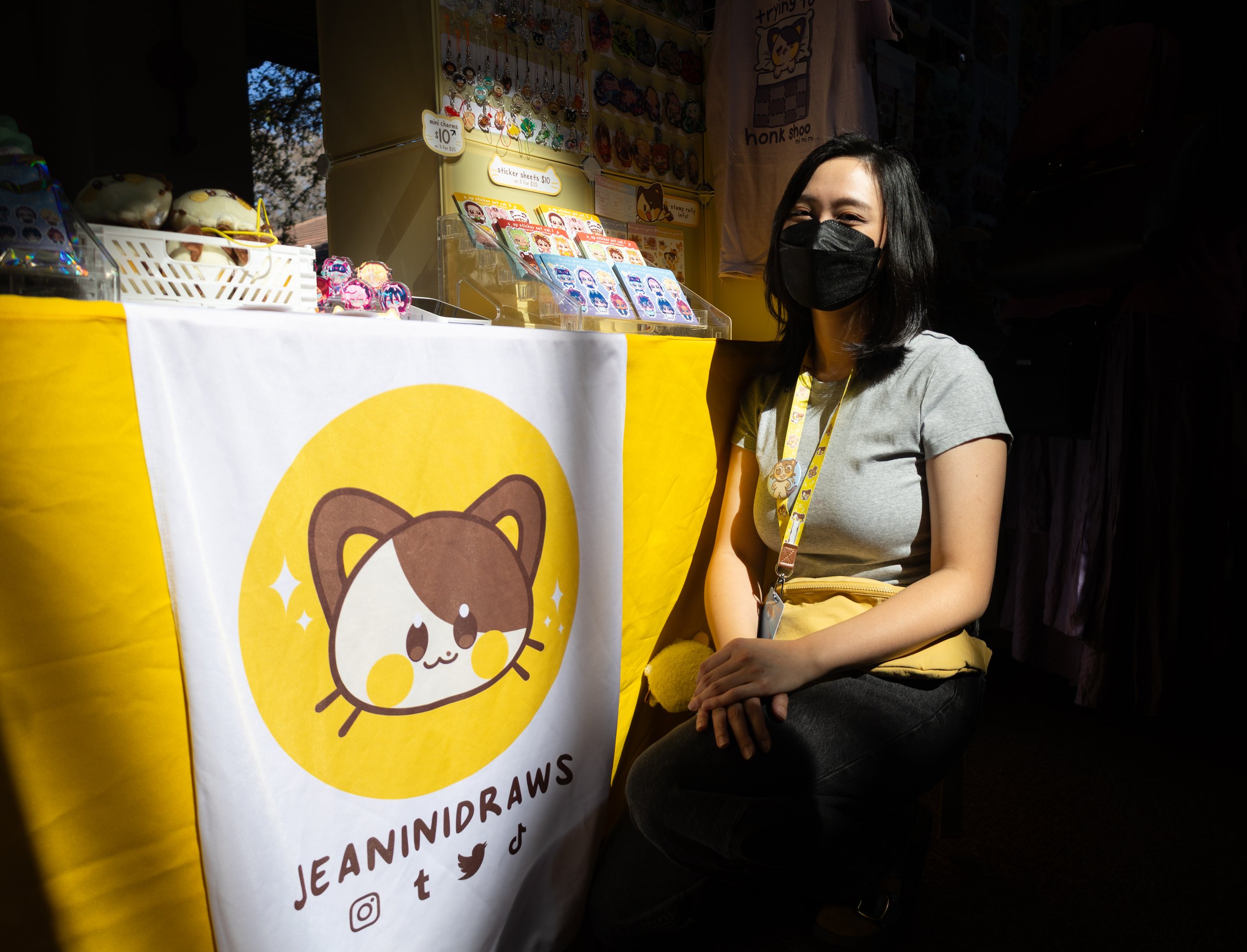 Jeaninidraws poses in front of her vendor table at KumoriCon's Artist Alley on Feb. 7, 2026