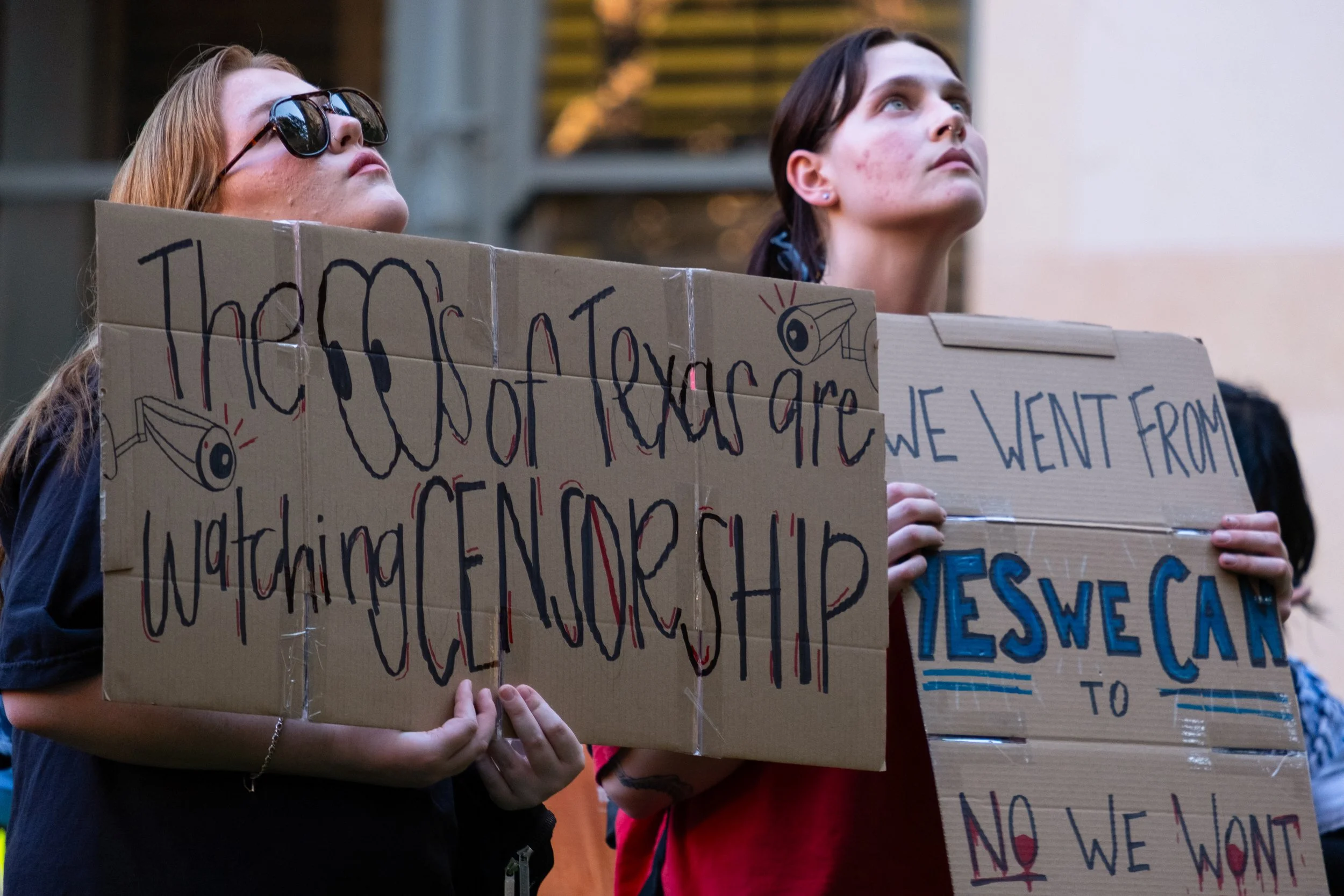 Protesters hold signs as they listen to a speaker from the bottom of an external stairwell located near the tower on campus on Nov. 7.