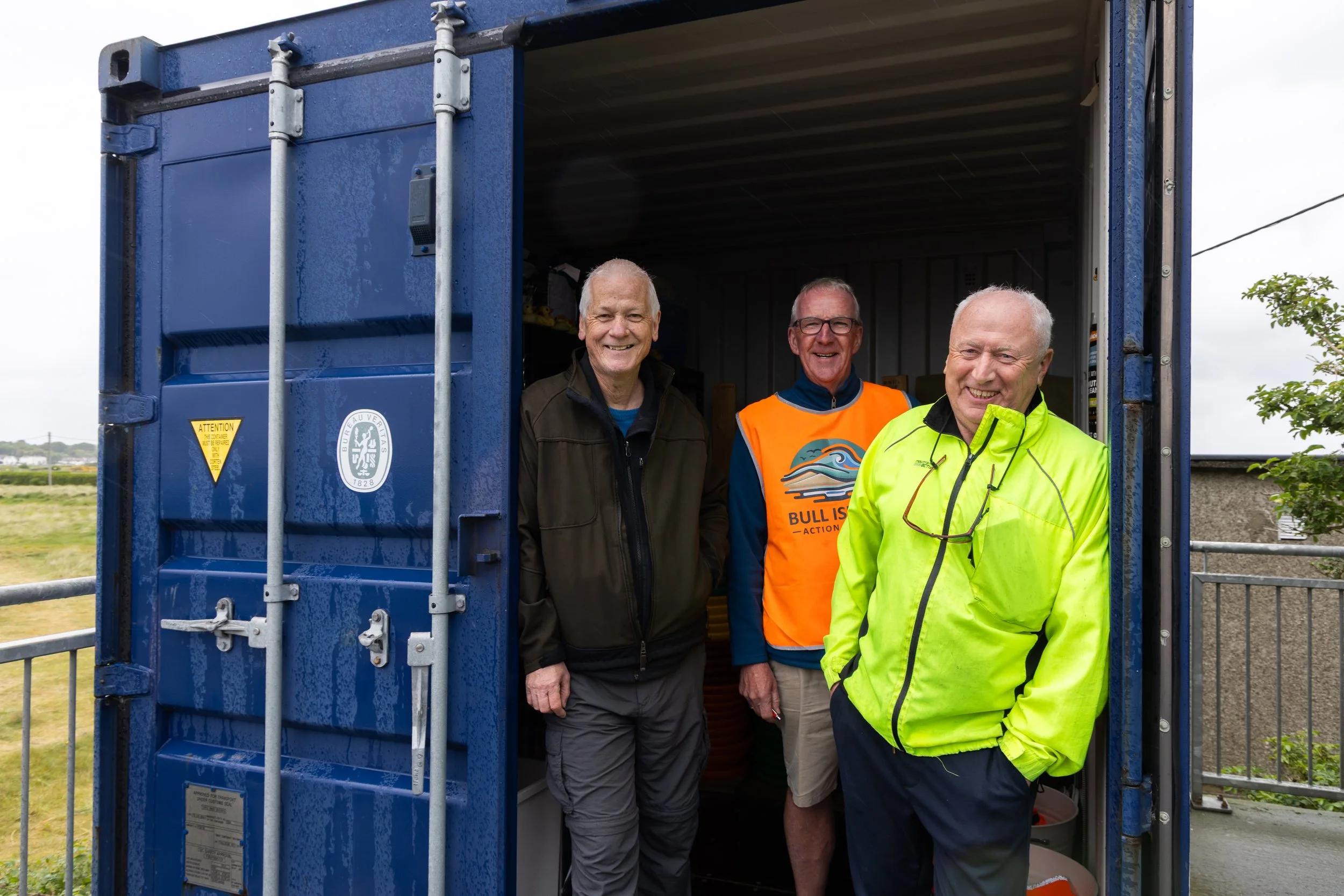 Left to right, Stephen O'Shea, Tom Maginn and Dave Ryan pose from inside Bull Island Action Group's storage unit at Dollymount Beach in Dublin, Ireland on May 16, 2025. 