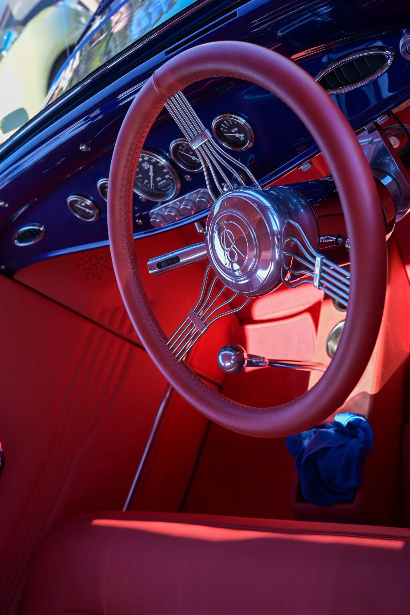 Interior of a vintage car with a red dashboard, steering wheel, and gauges.