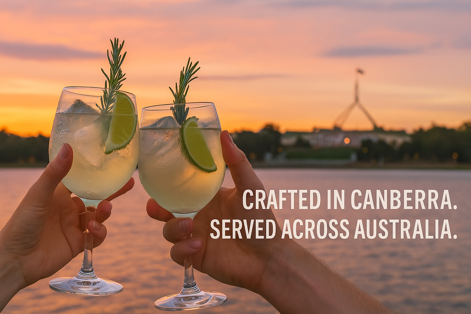 Two hands holding glasses of a cocktail garnished with lime slices and rosemary sprigs, with a sunset over water in the background.