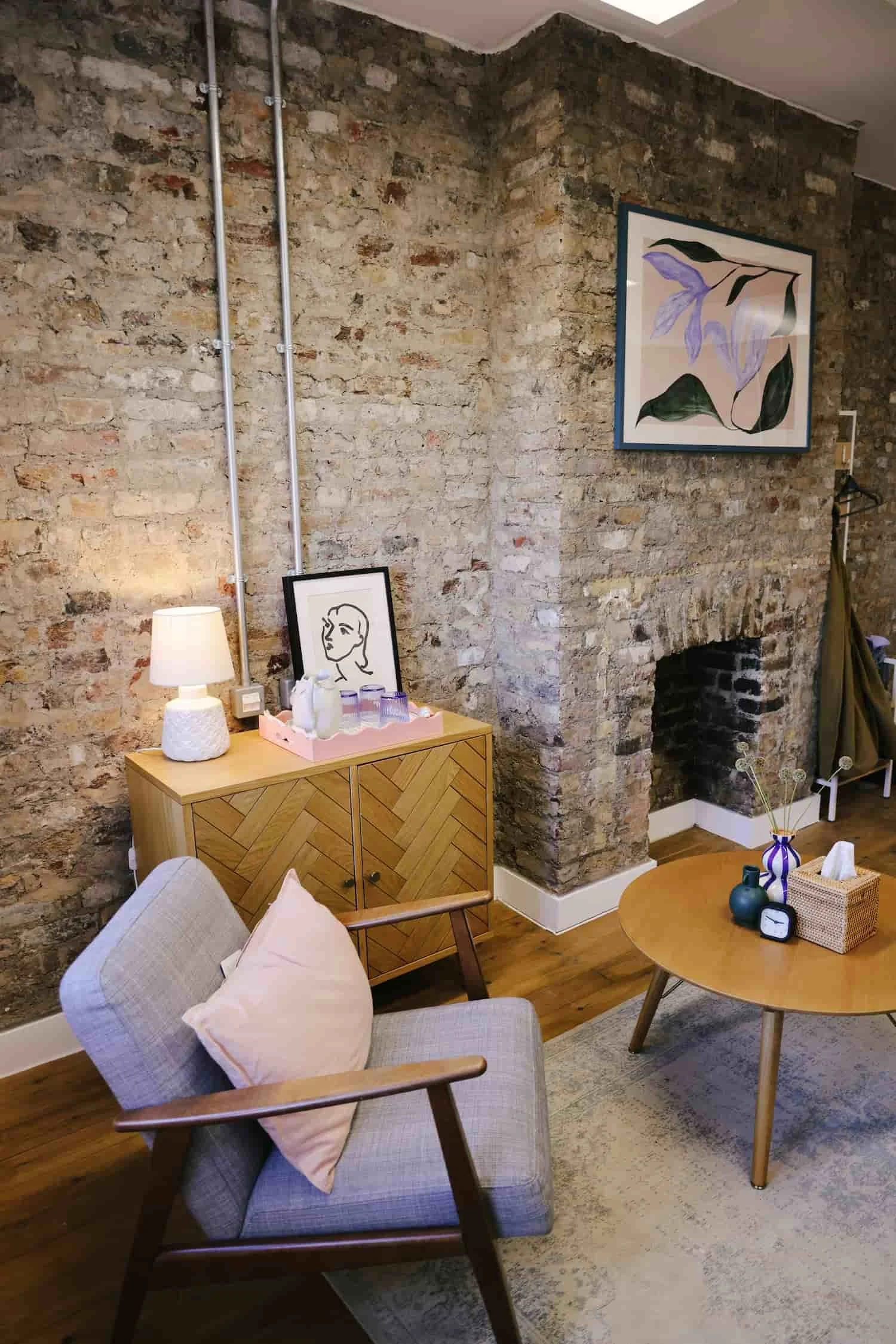 Warm therapy room interior with armchair and exposed brick wall in Brixton, South London consulting room