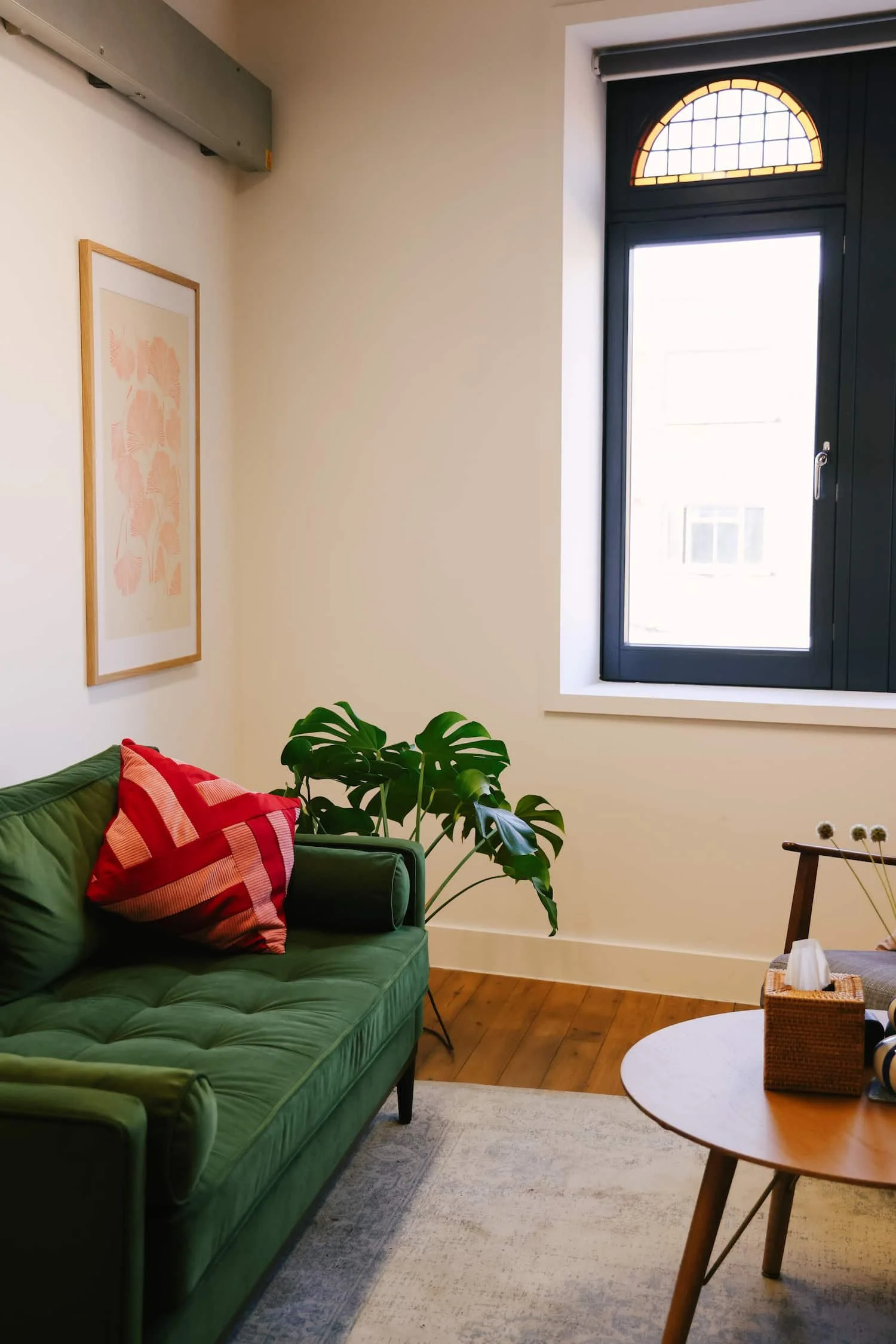 Light-filled counselling room with green sofa and window