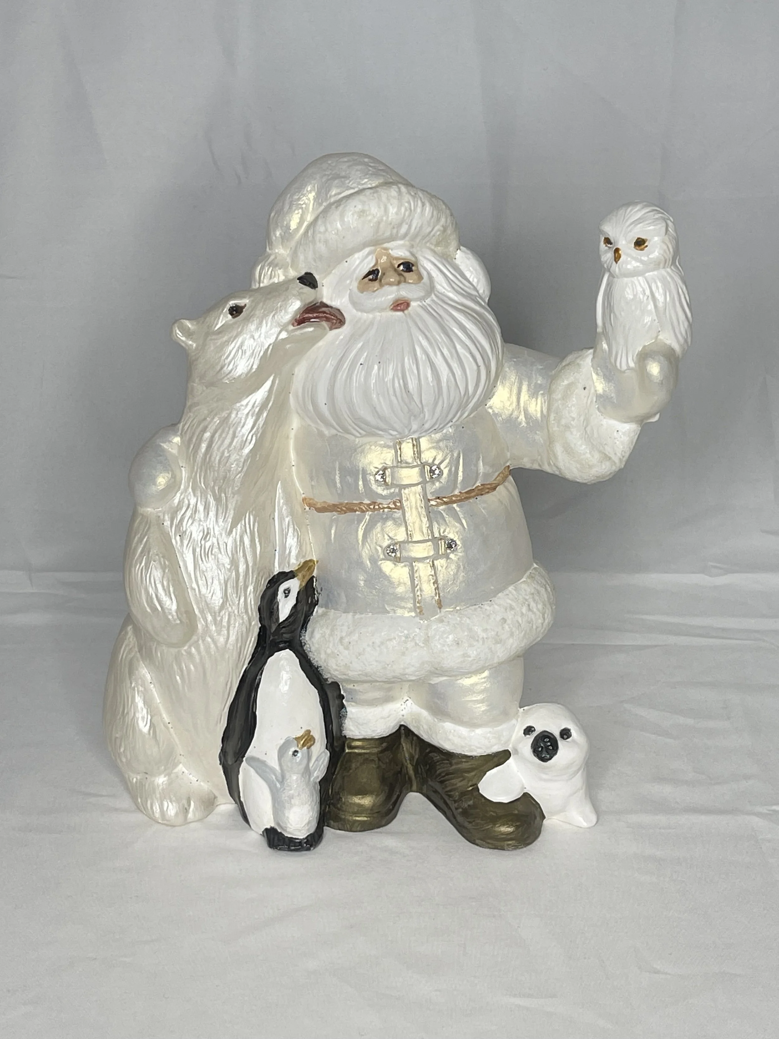 Christmas Santa Claus figurine holding an owl, with a polar bear, penguin, and seal surrounding him.
