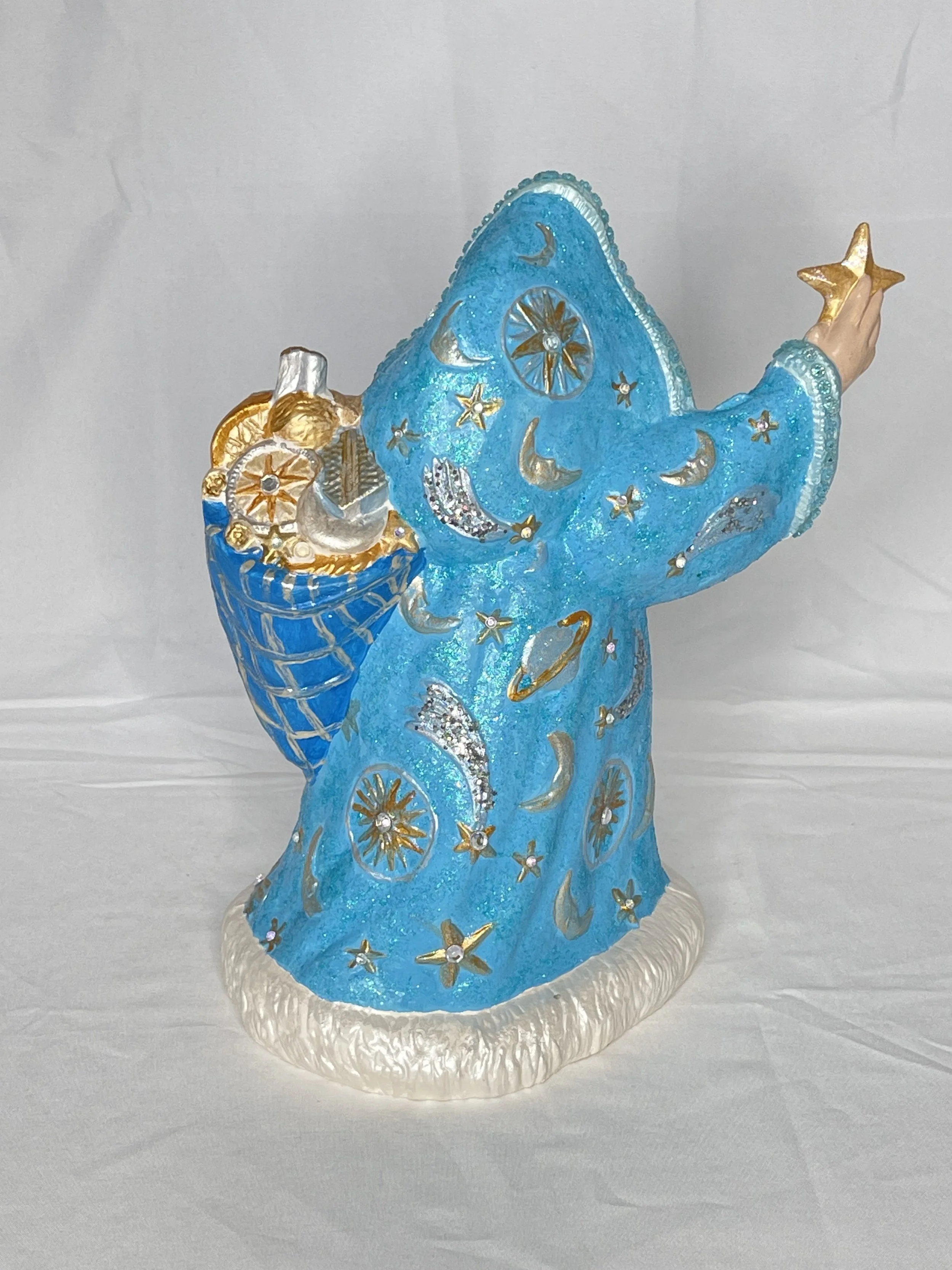 Blue wizard figurine holding a gold star, decorated with moons, stars, planets, and cosmic patterns.