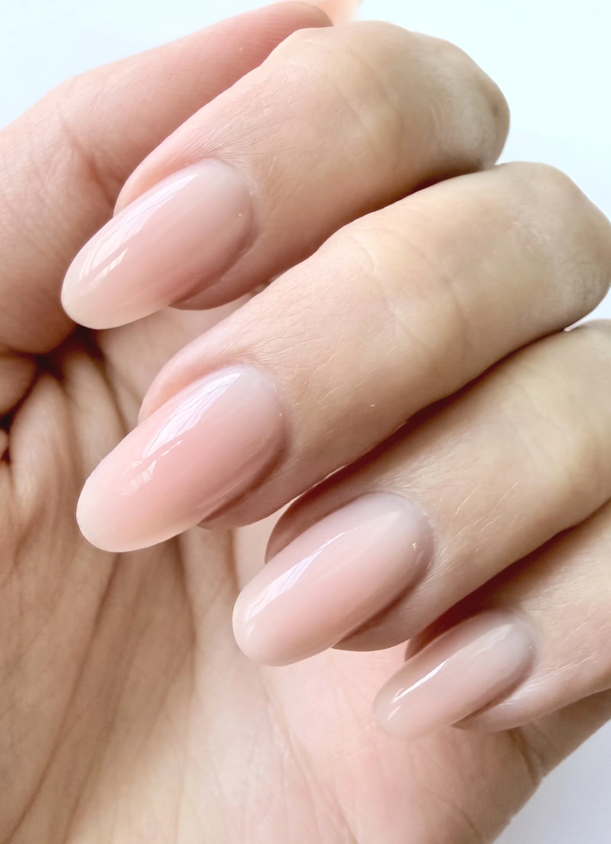 Close-up of a hand with natural nails showing a slight shine, holding or touching bare skin.