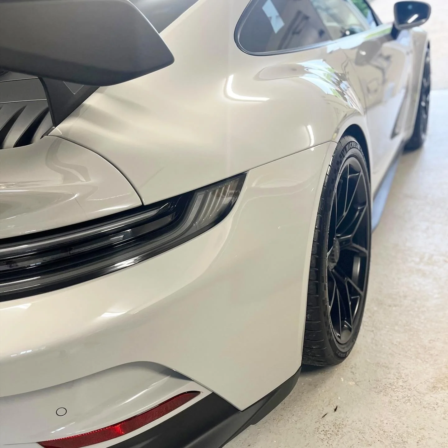 Close-up of the front left side of a white sports car after a full detail valet by Oxford Car Detailing.