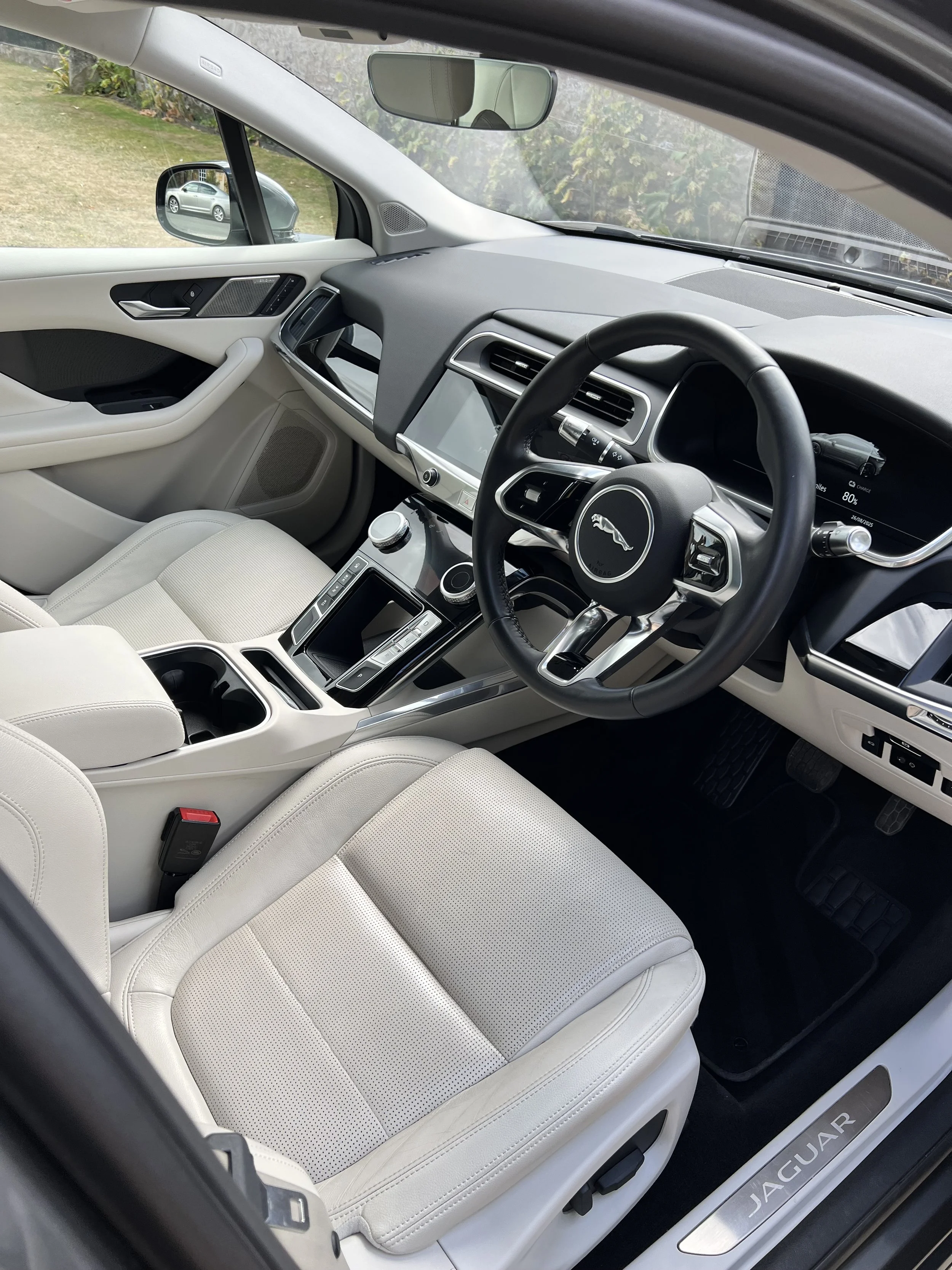 Interior of a white Jaguar vehicle showing the dashboard, steering wheel, front seats, and center console after full valet and detailing..