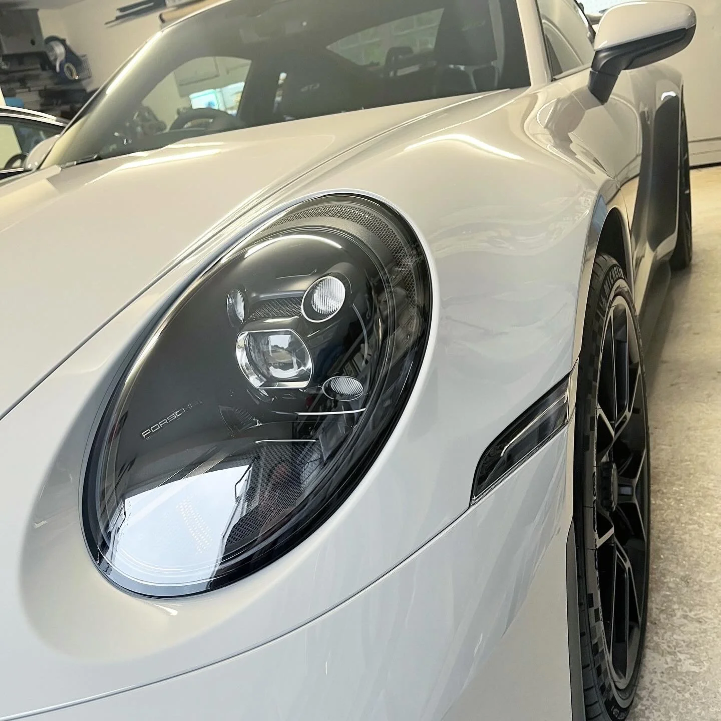 Close-up of the front left side of a white Porsche sports car after a full detail valet by Oxford Car Detailing.