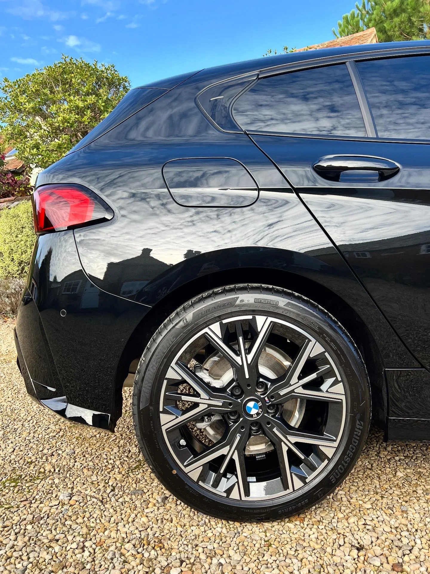 Close-up of the rear side of a shiny black BMW car after full valet and detail and ceramic coating.