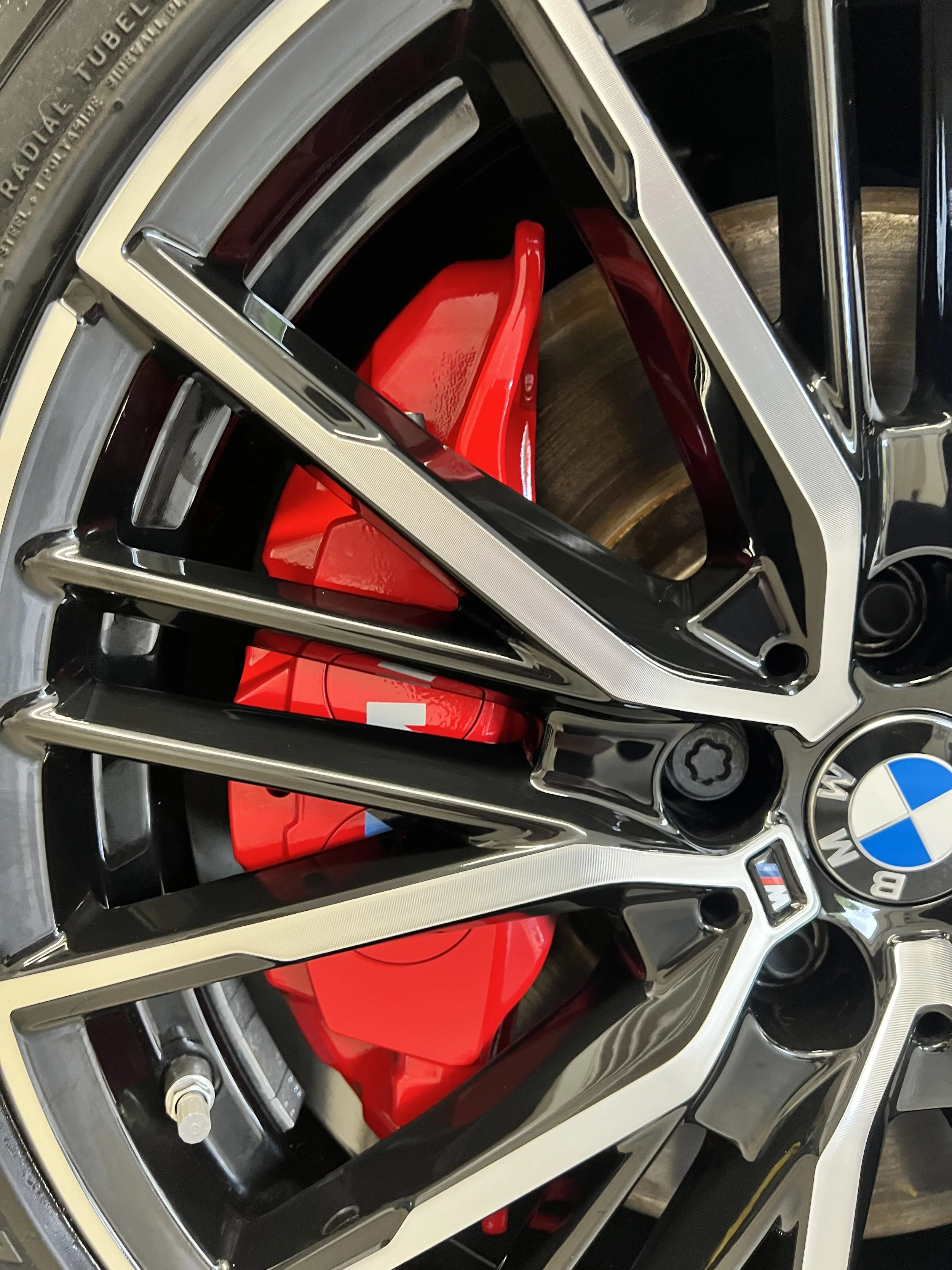 Close-up of BMW car wheel rims with red brake calipers visible through the spokes.