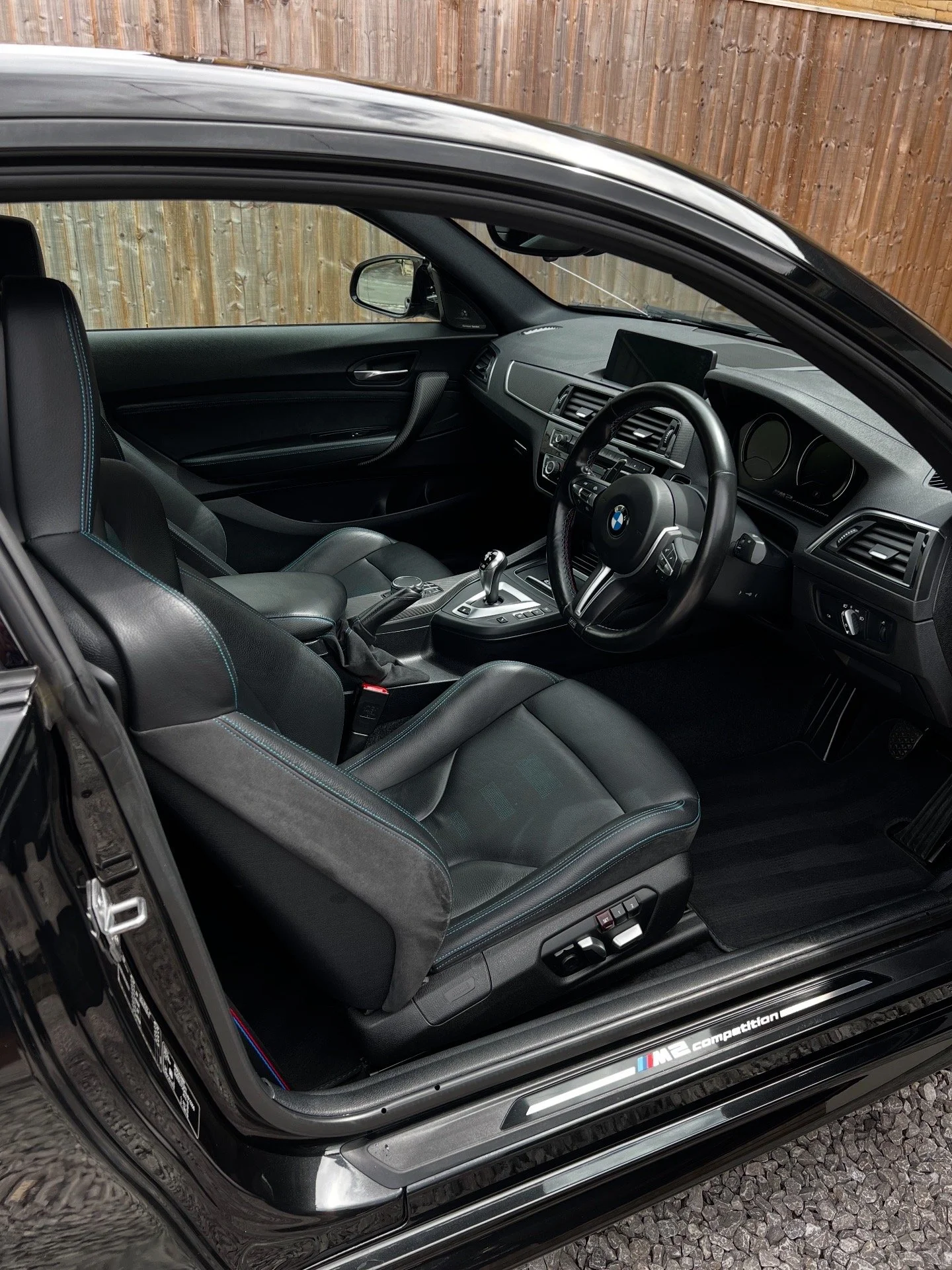 Interior of a BMW M2 Competition with black leather seats, dashboard, and steering wheel after full interior valet.