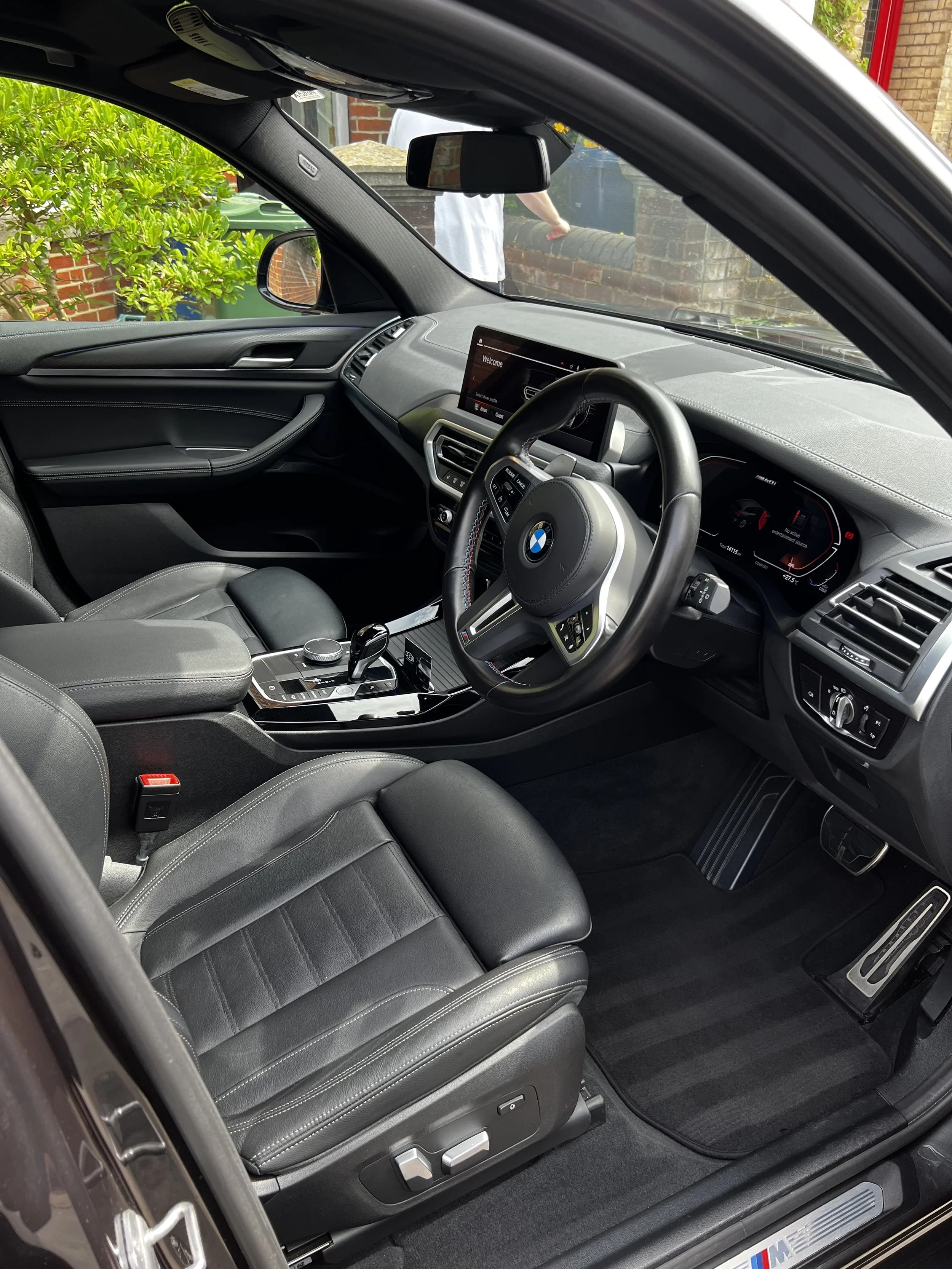 Interior of a BMW vehicle featuring black leather seats, a digital dashboard, and a centre console with gear shift and control buttons after interior valet.