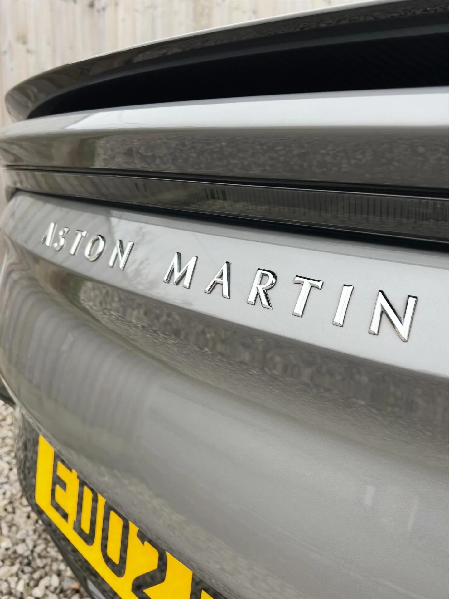 Close-up of the rear of a silver car, displaying the badge with the words '1.5 TON MARTIN' and a partial view of a yellow license plate.