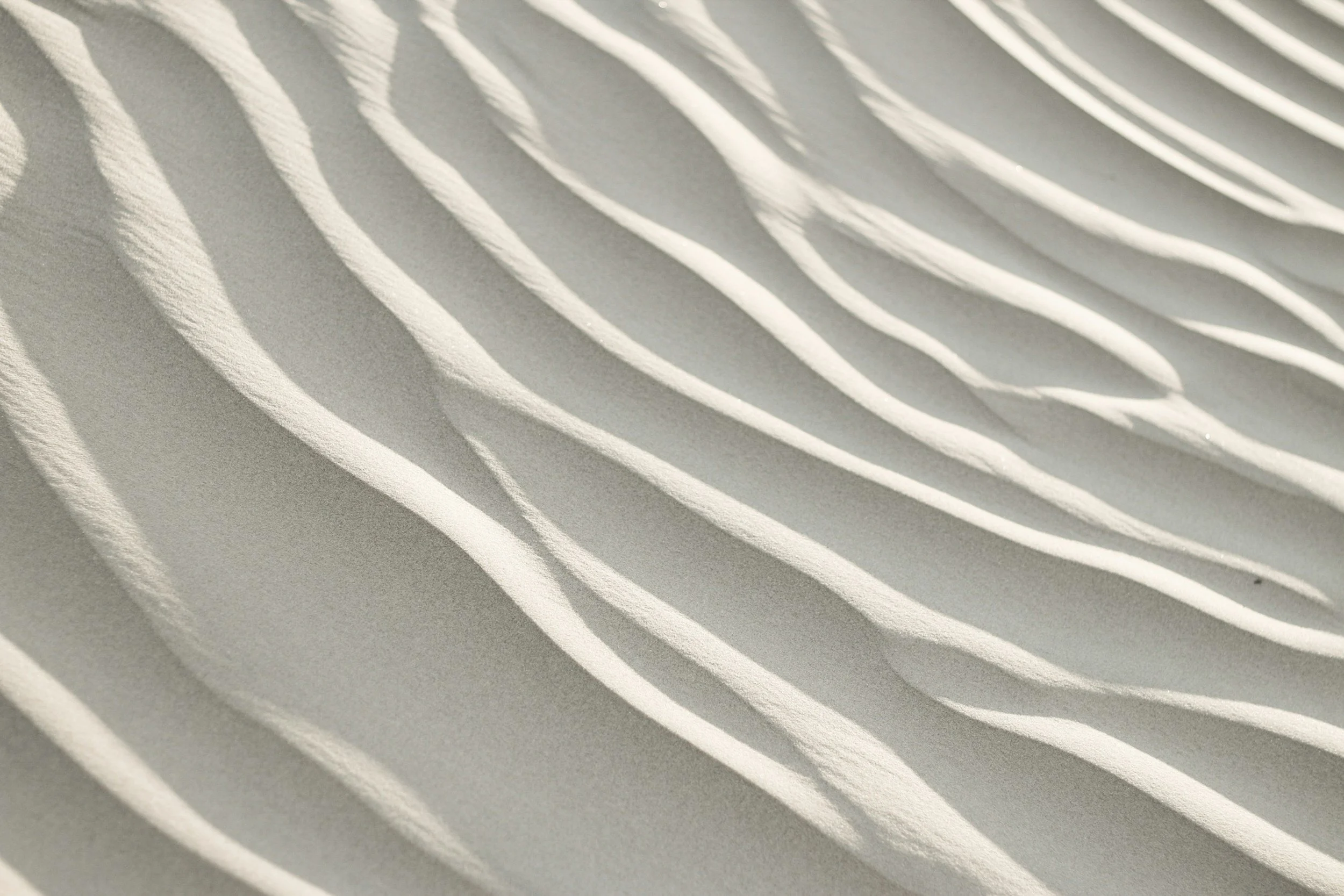Close-up of white sand with wind-created ripples.