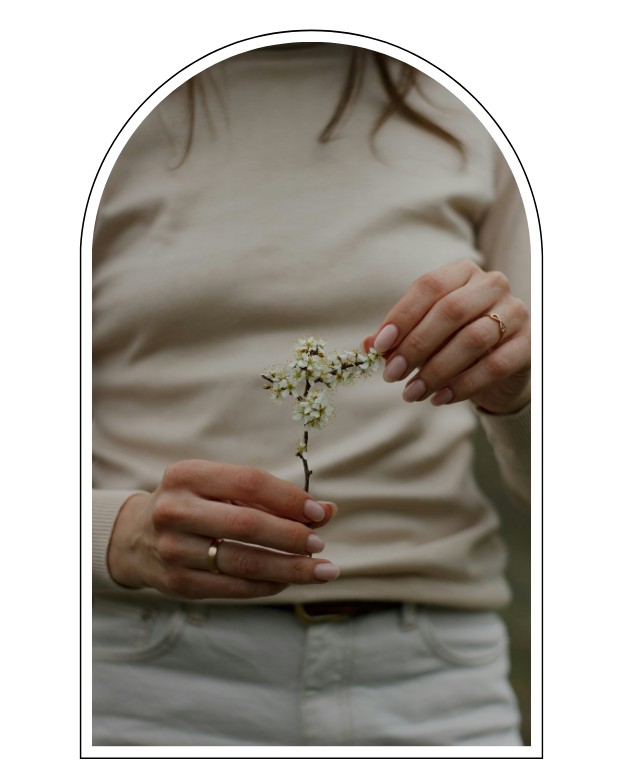 Person holding a small branch with white blossoms.