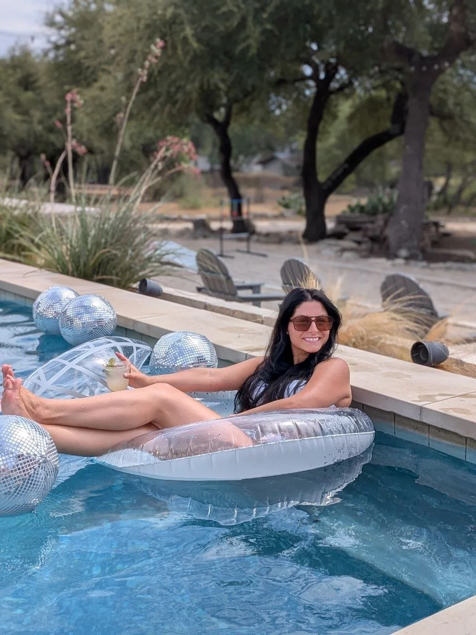  The bride to be floats in a hill country pool with a drink in her hand 
