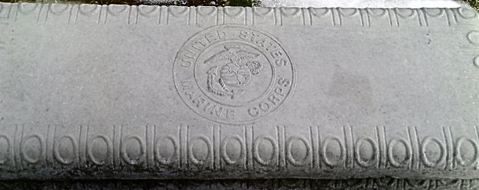 Close-up of a rectangular stone with the emblem and inscription of the United States Marine Corps carved into it.