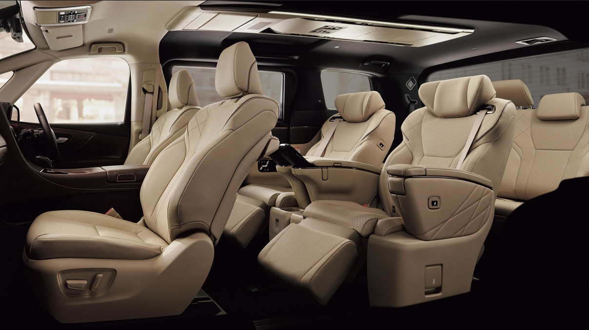 Interior of a luxury van with beige leather seats, including captain's chairs and a bench seat, with a clean and modern design.
