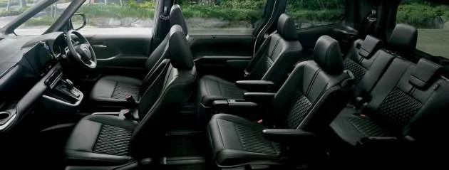 Inside view of a black minivan with multiple rows of black leather seats.