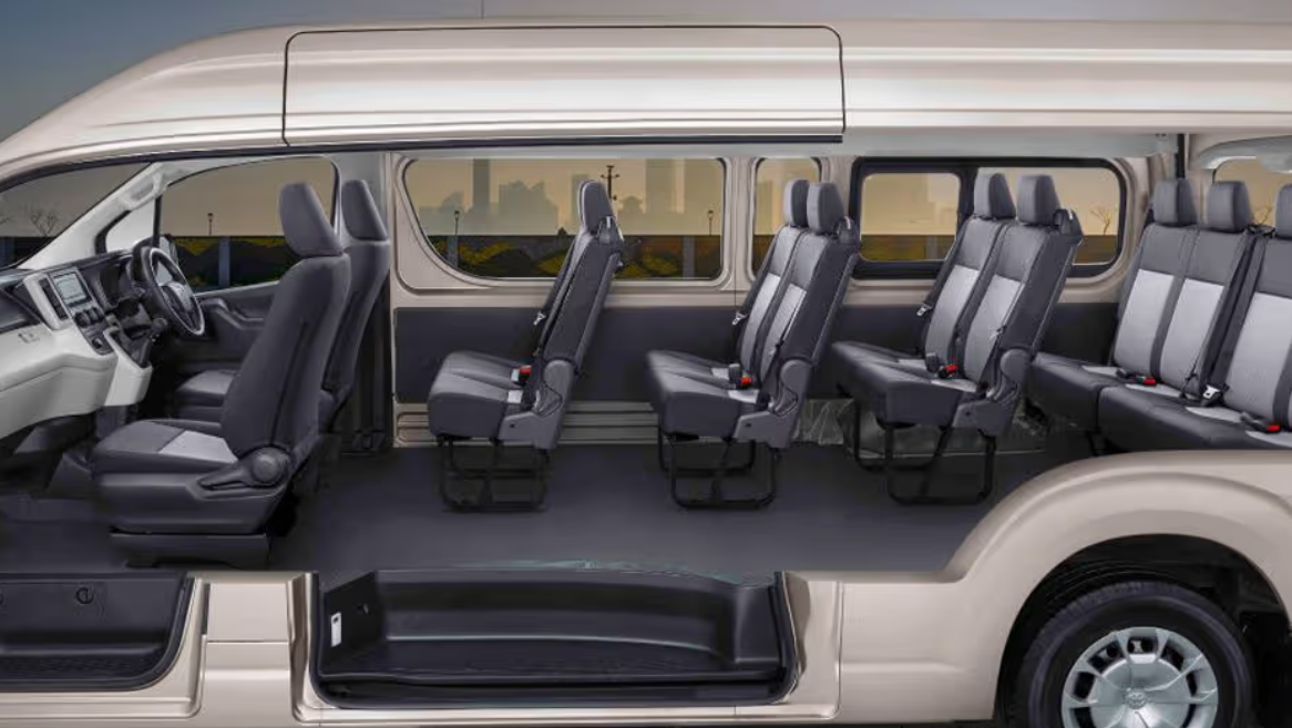 Interior of a passenger van with several gray seats arranged in multiple rows, facing forward.