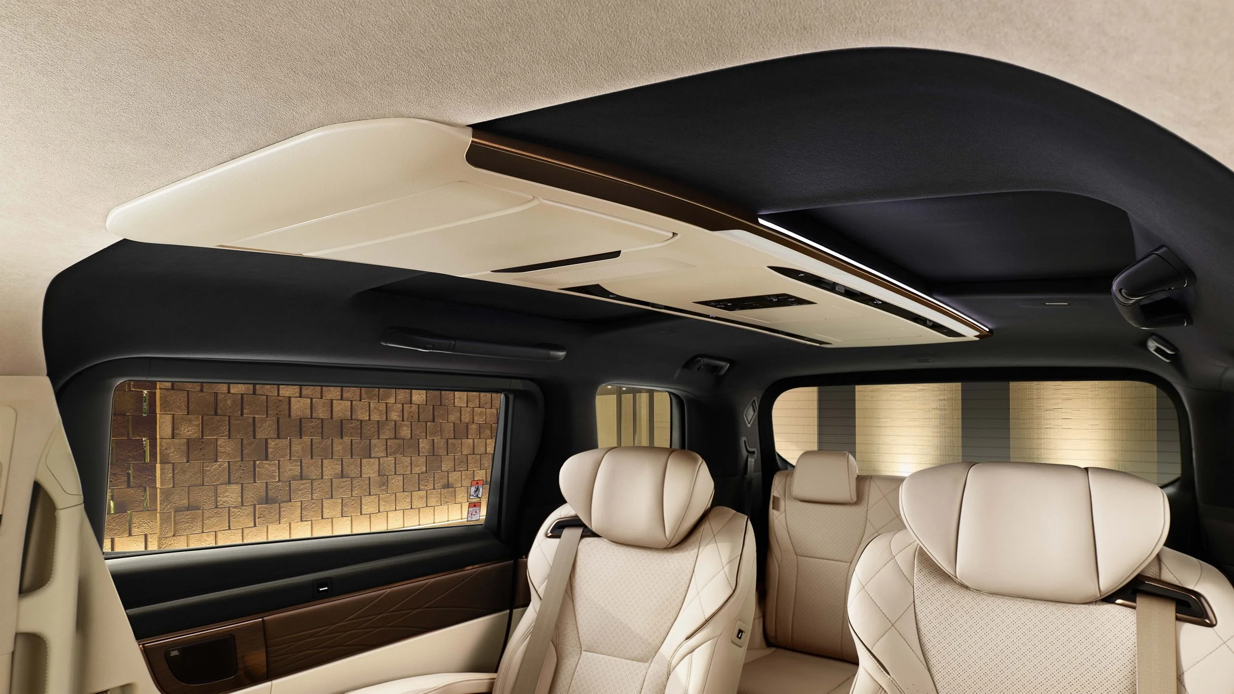 Interior of a luxury vehicle showing beige leather seats, large windows, and a ceiling panel with ambient lighting.