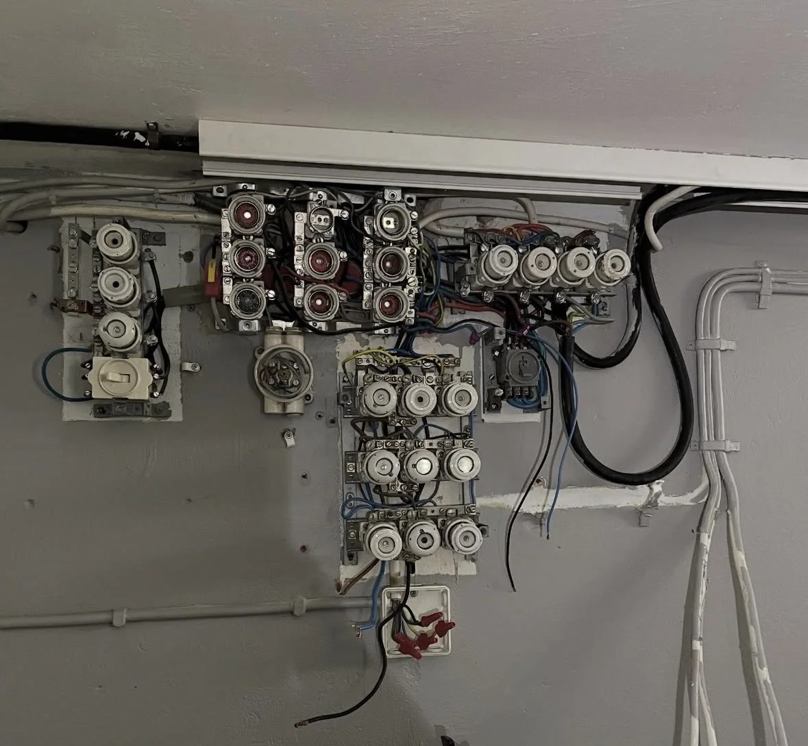 Elcentral med flera elektriska komponenter och kopplingar. En gammal osäker elcentral som kräver ett byte för bättre säkerhet, vilket vi kan erbjuda!