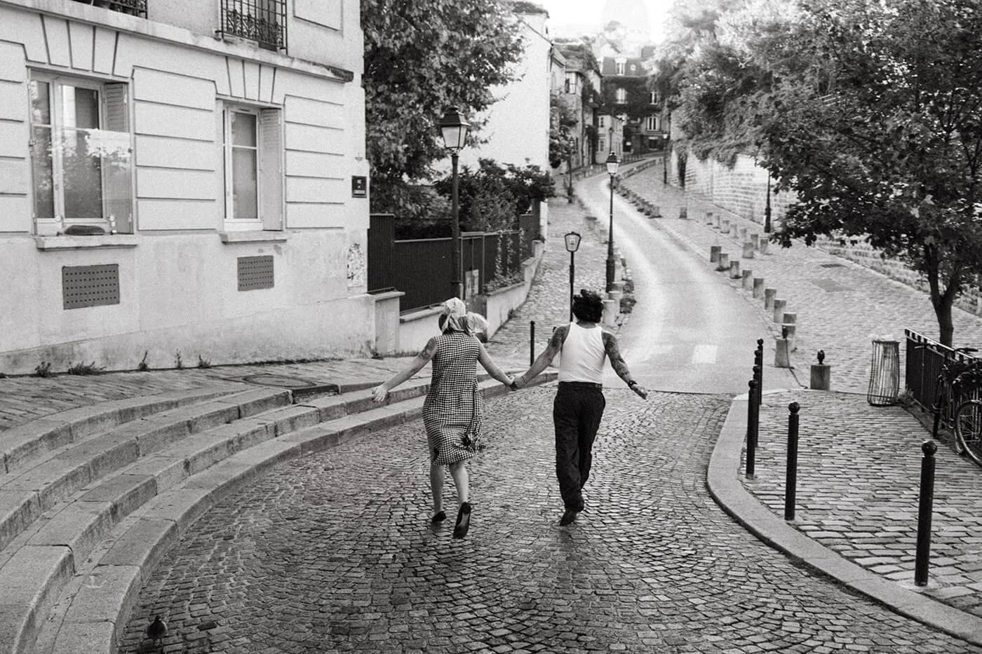 Playful couple during their engagement session in Paris on a cobblestone street in Montmartre, captured by a Paris engagement photographer in soft natural light.