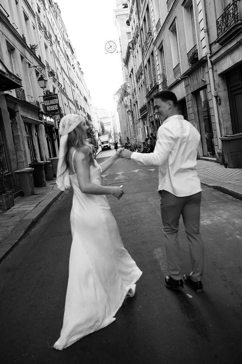 Black and white photo of a joyful couple walking hand in hand in Paris, candid elopement moment captured by a Paris elopement photographer.