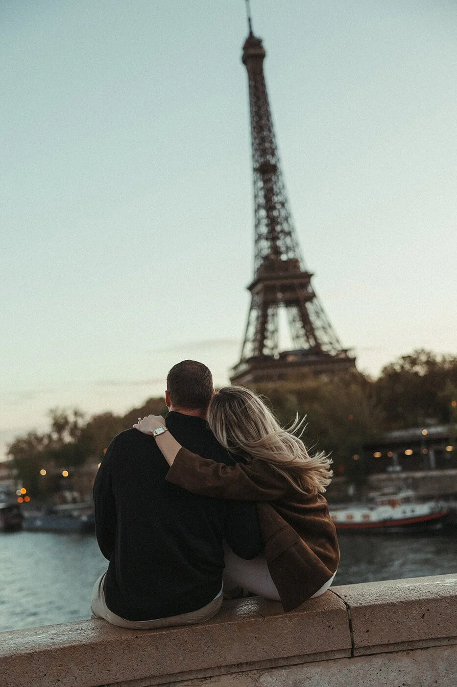 Romantic couple portrait in Paris with the Eiffel Tower framed by a stone balustrade.