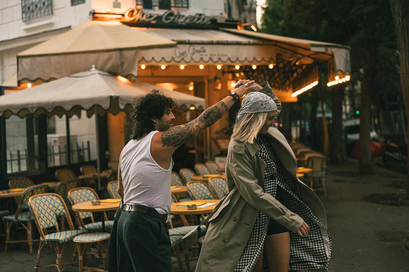 Playful couple moment at a Paris café during their engagement session, cinematic and romantic Montmartre photography.