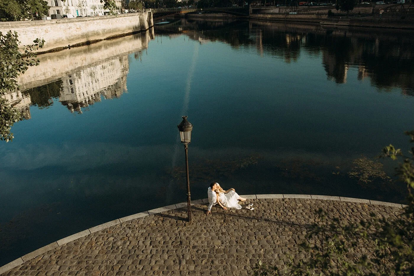 Romantic couple embracing under a Parisian lamppost during their engagement session in Paris, cinematic evening atmosphere.