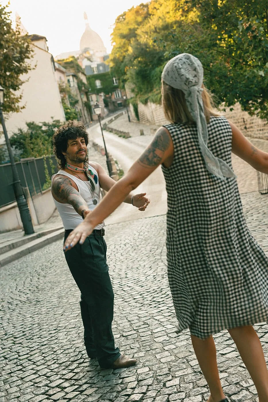 Couple twirling on cobblestone streets in Paris during a romantic engagement session, natural movement captured by a Paris engagement photographer.