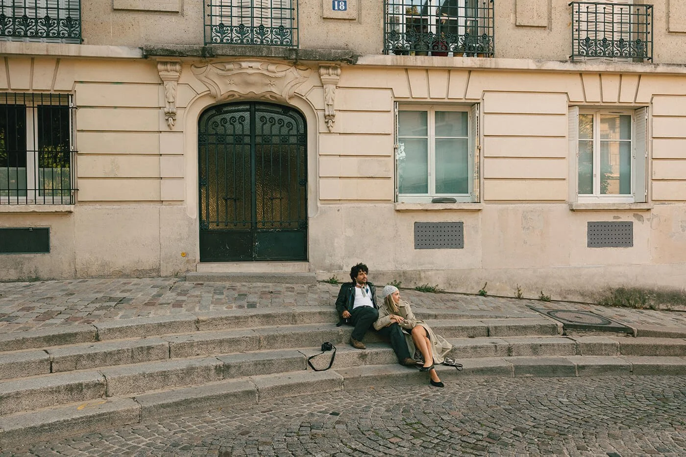 Playful couple sitting on steps in Montmartre during their Paris engagement session, relaxed and authentic love story photography.